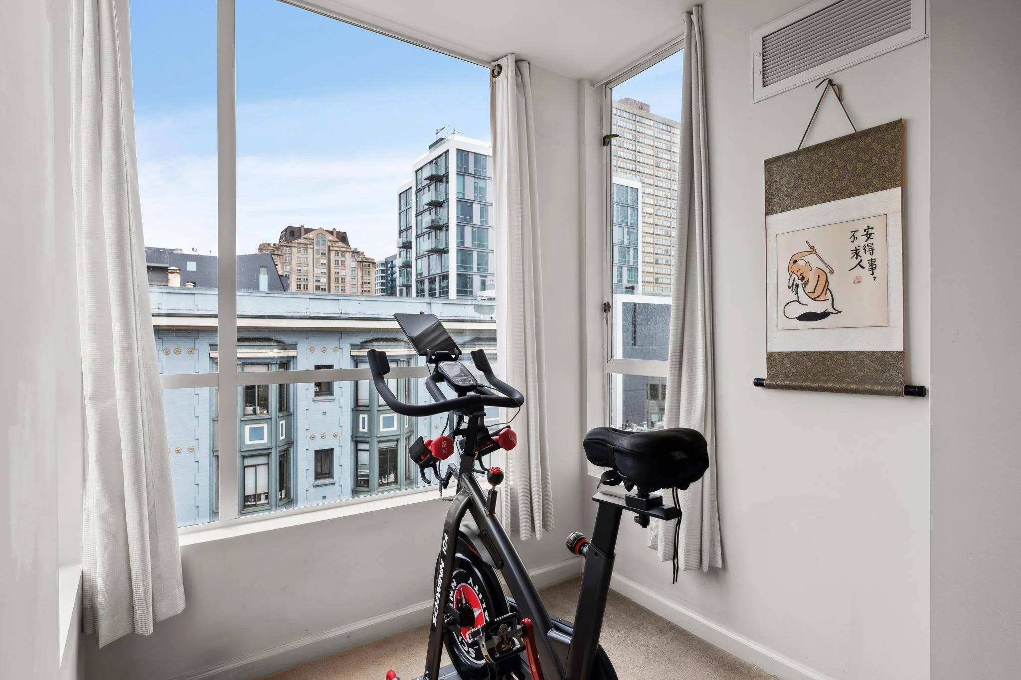 Indoor cycling bike in front of large windows with city buildings visible outside