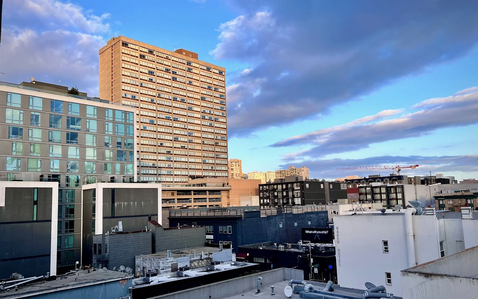 Cityscape of high-rise buildings and rooftops with a cloudy sky during sunset.