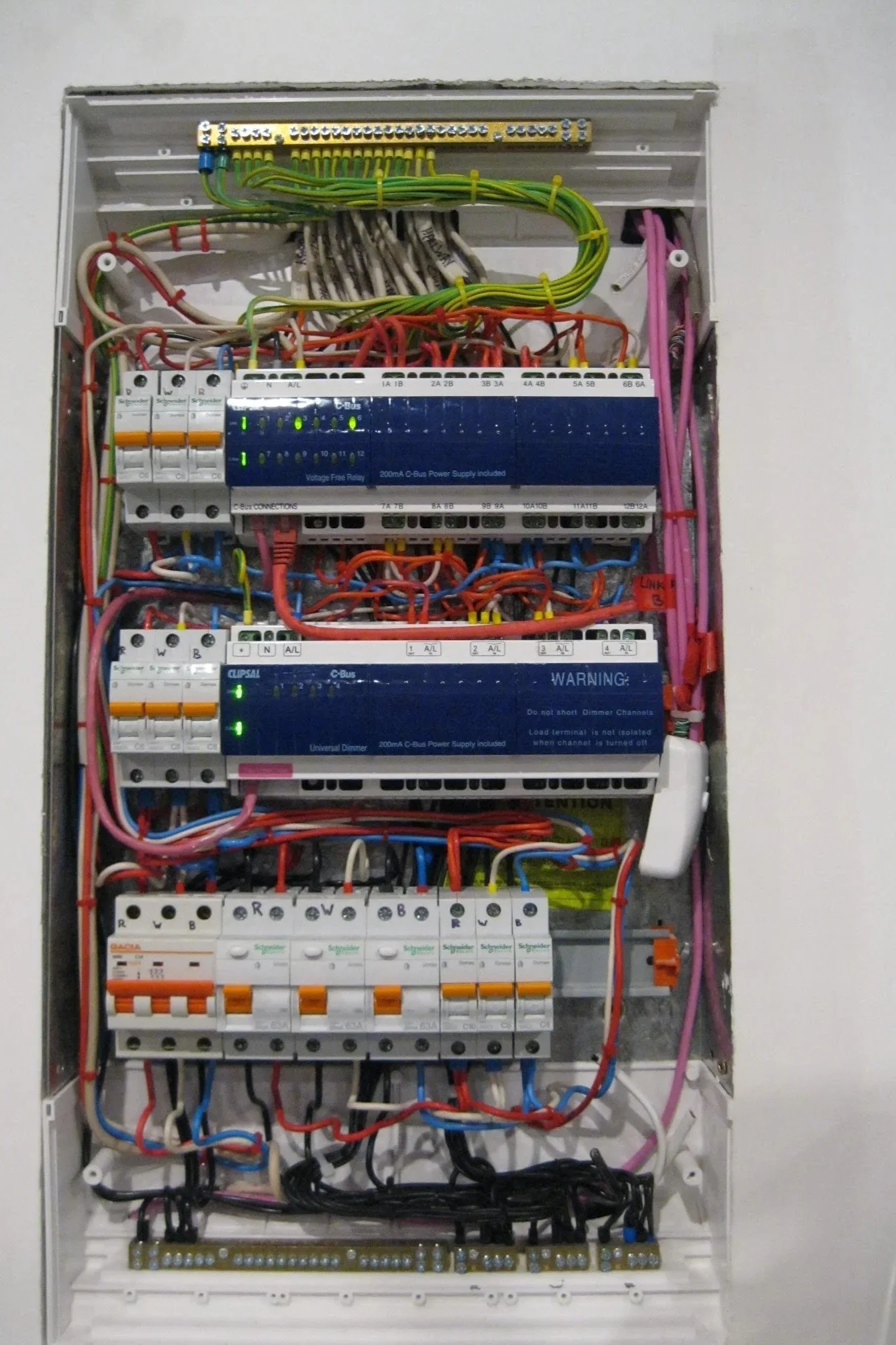 Electrical panel with various wires, circuit breakers, and control modules inside a white box.