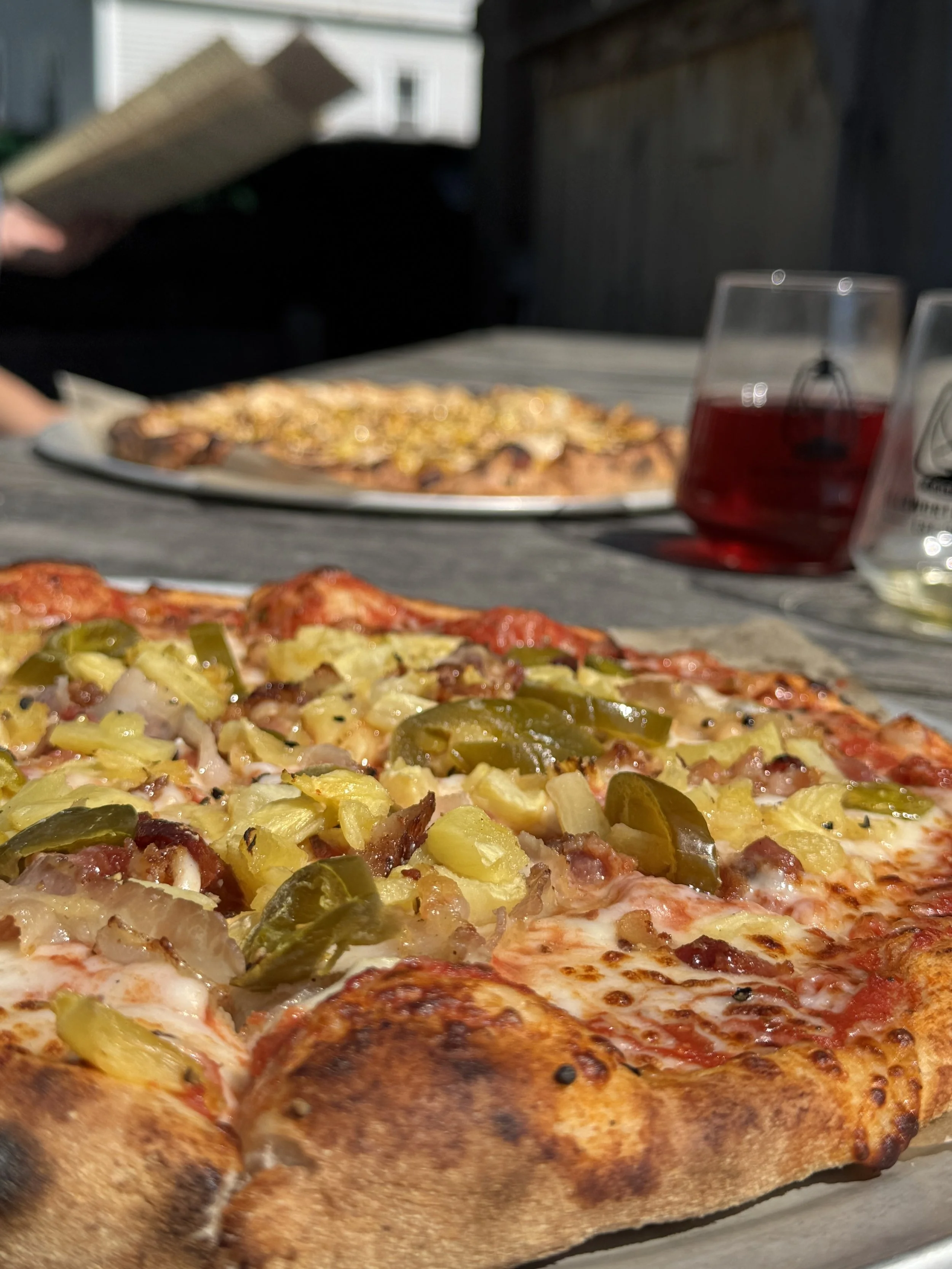 PIza close up with drink in the background.jpeg