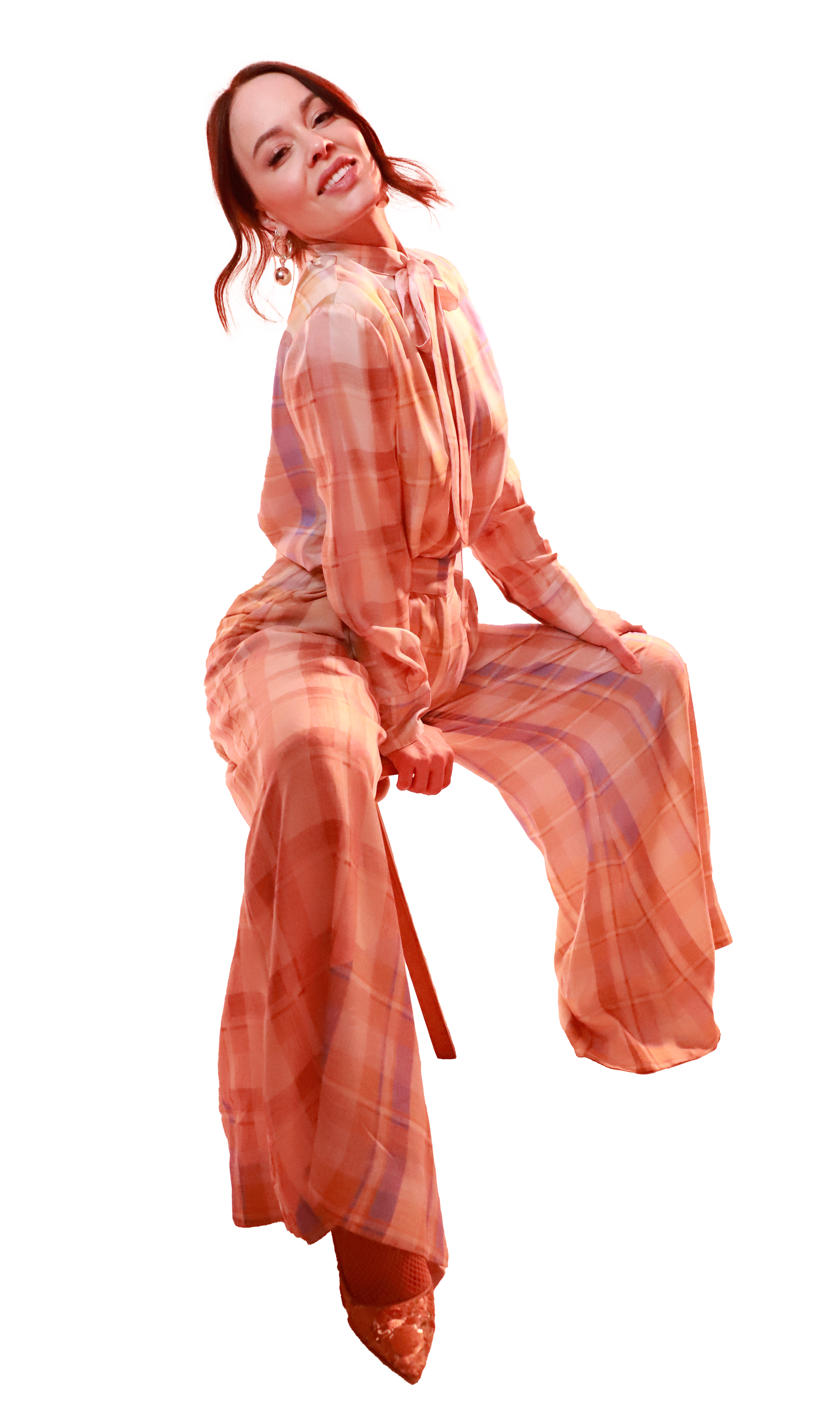 Dr. Elizabeth Love posing in a peach plaid jumpsuit with a chair.