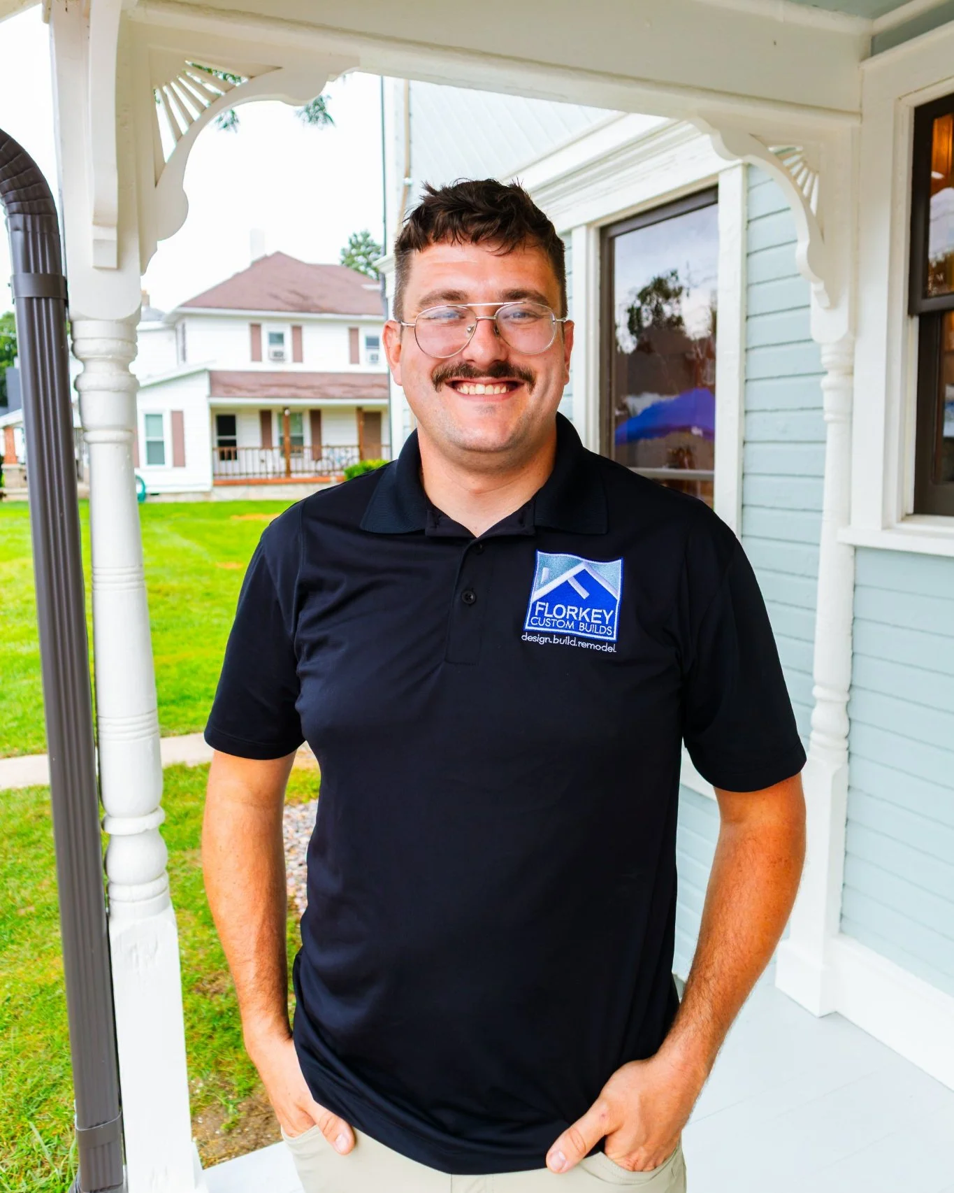 Garrett Guthrie of Florkey Custom Builds standing on the porch of a restored Victorian home in Brookville, Ohio.