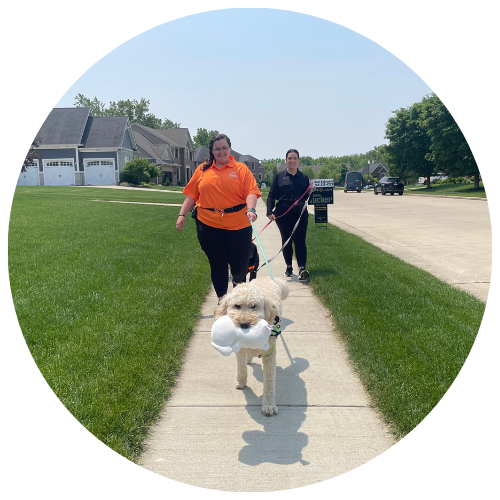 Walk Your Doggo pet caretaker in uniform smiling in front of pet-friendly apartment