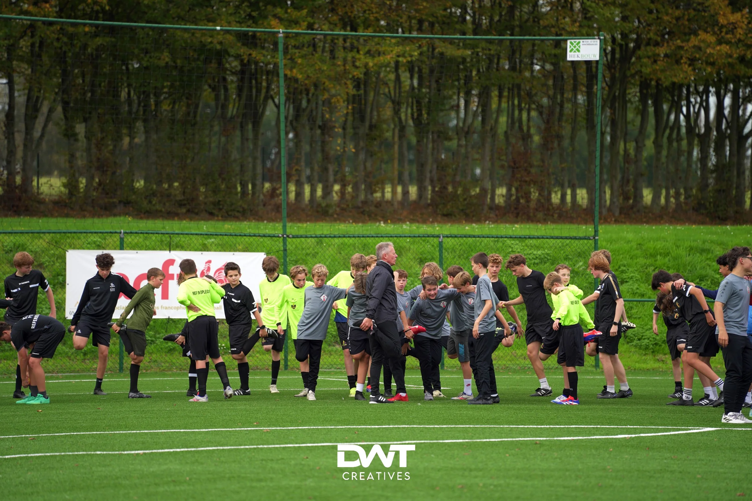 Jonge voetballers op het veld bezig met warming-up oefeningen.