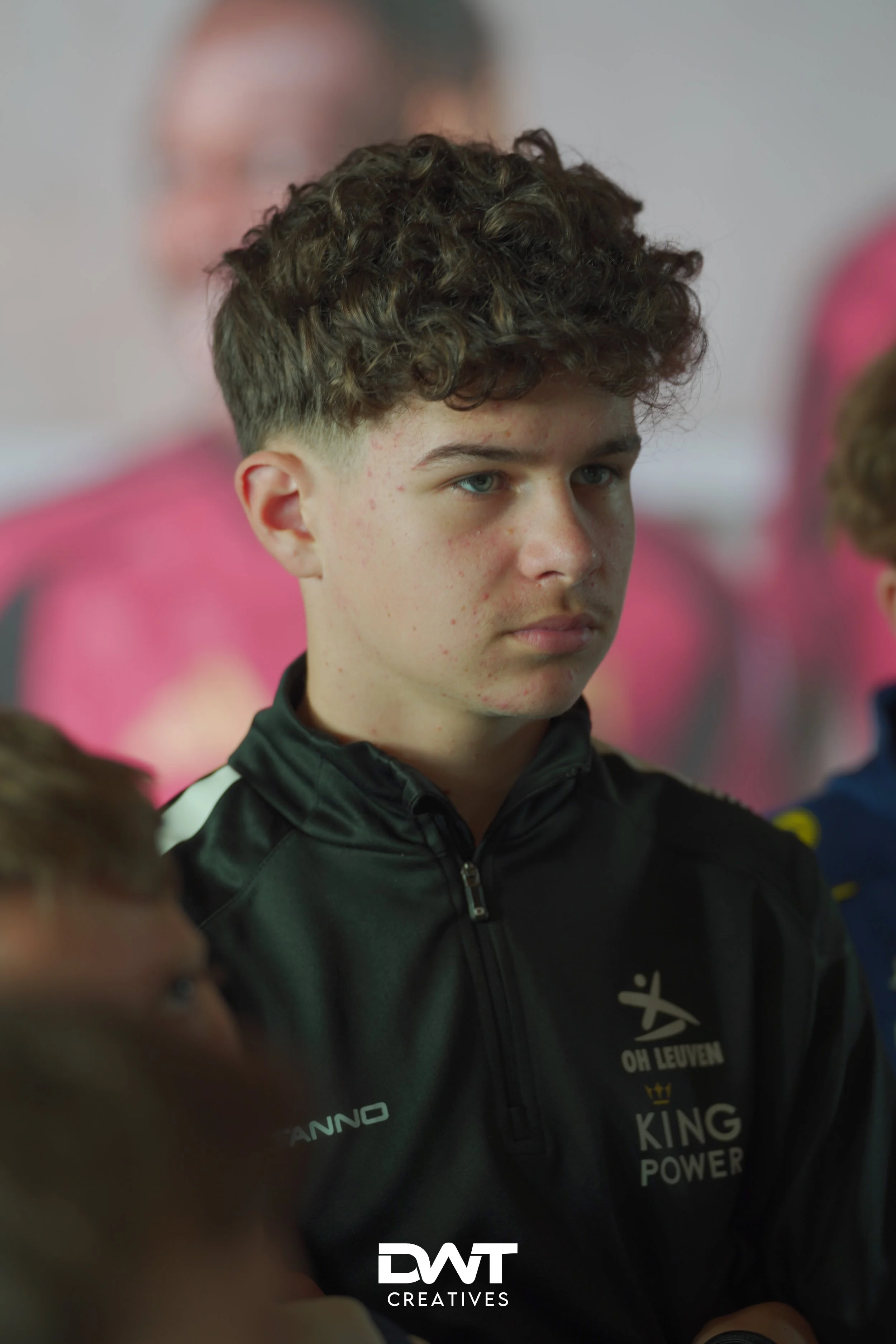 Jongen in sportkleding met logo's "Oh Leuven" en "King Power" op de trui. Achtergrond is onscherp.