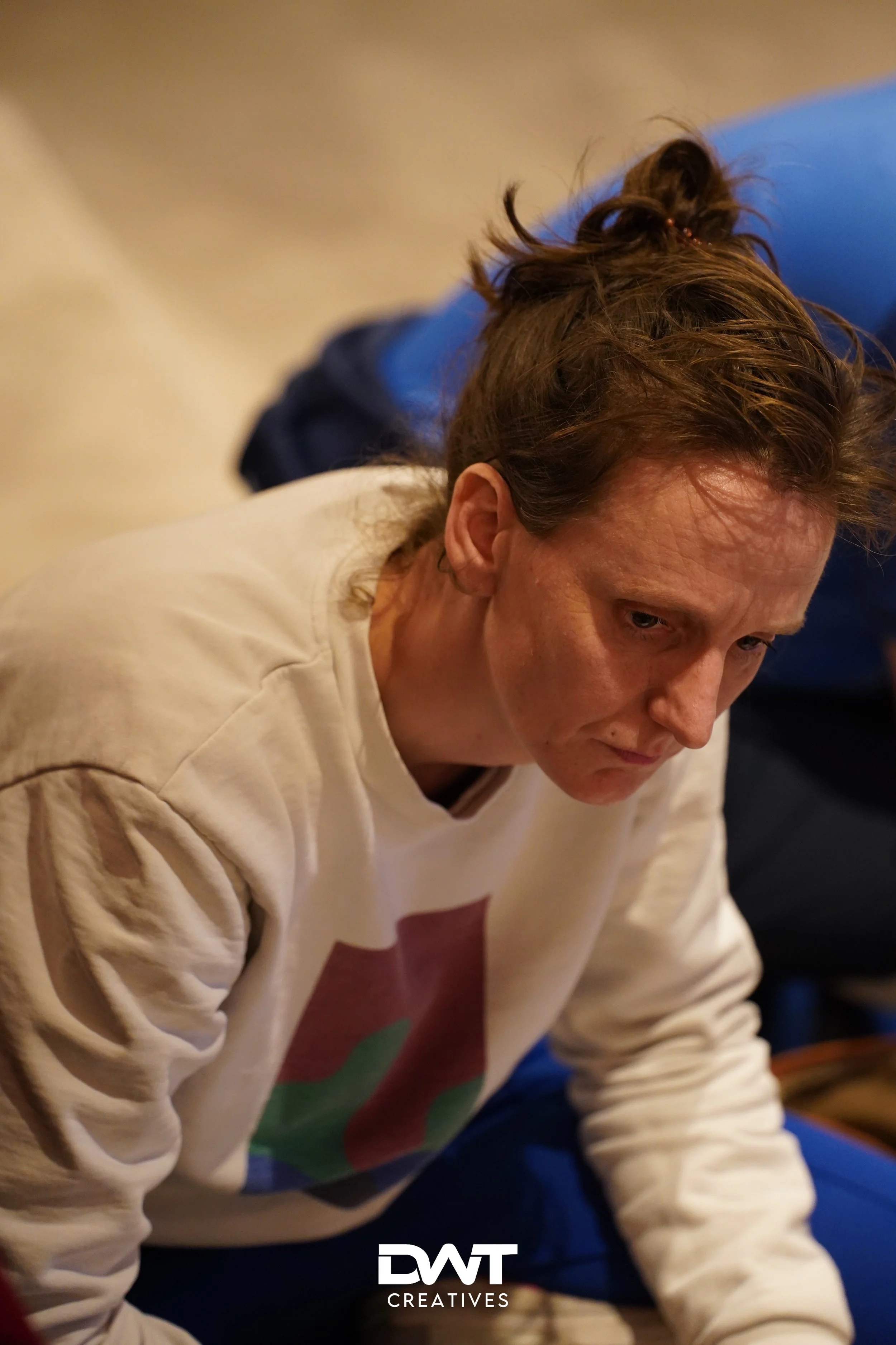 Persoon in witte trui, zittend in een geconcentreerde houding.