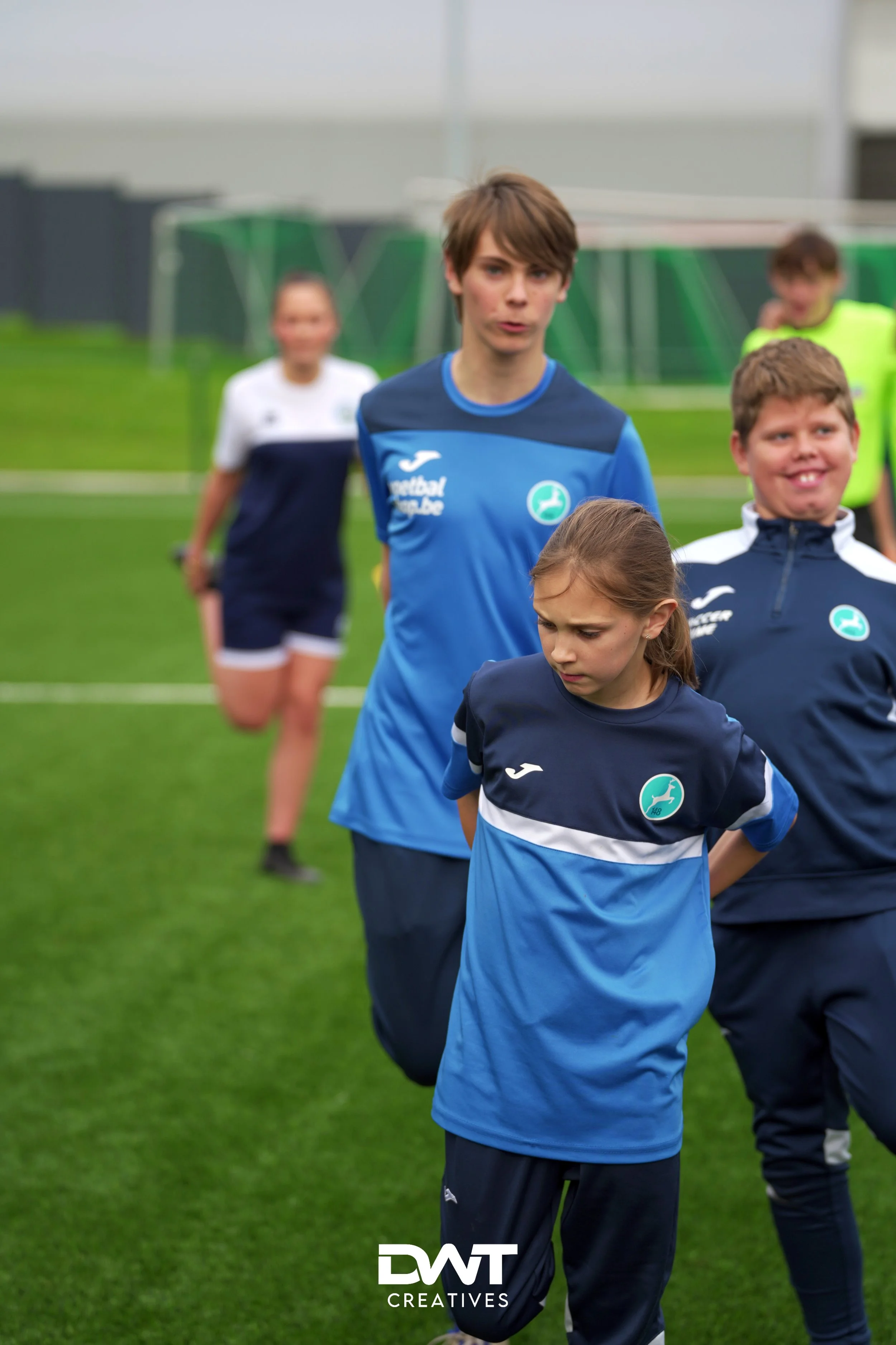 Kinderen in sportkleding op een voetbalveld tijdens een trainingssessie.