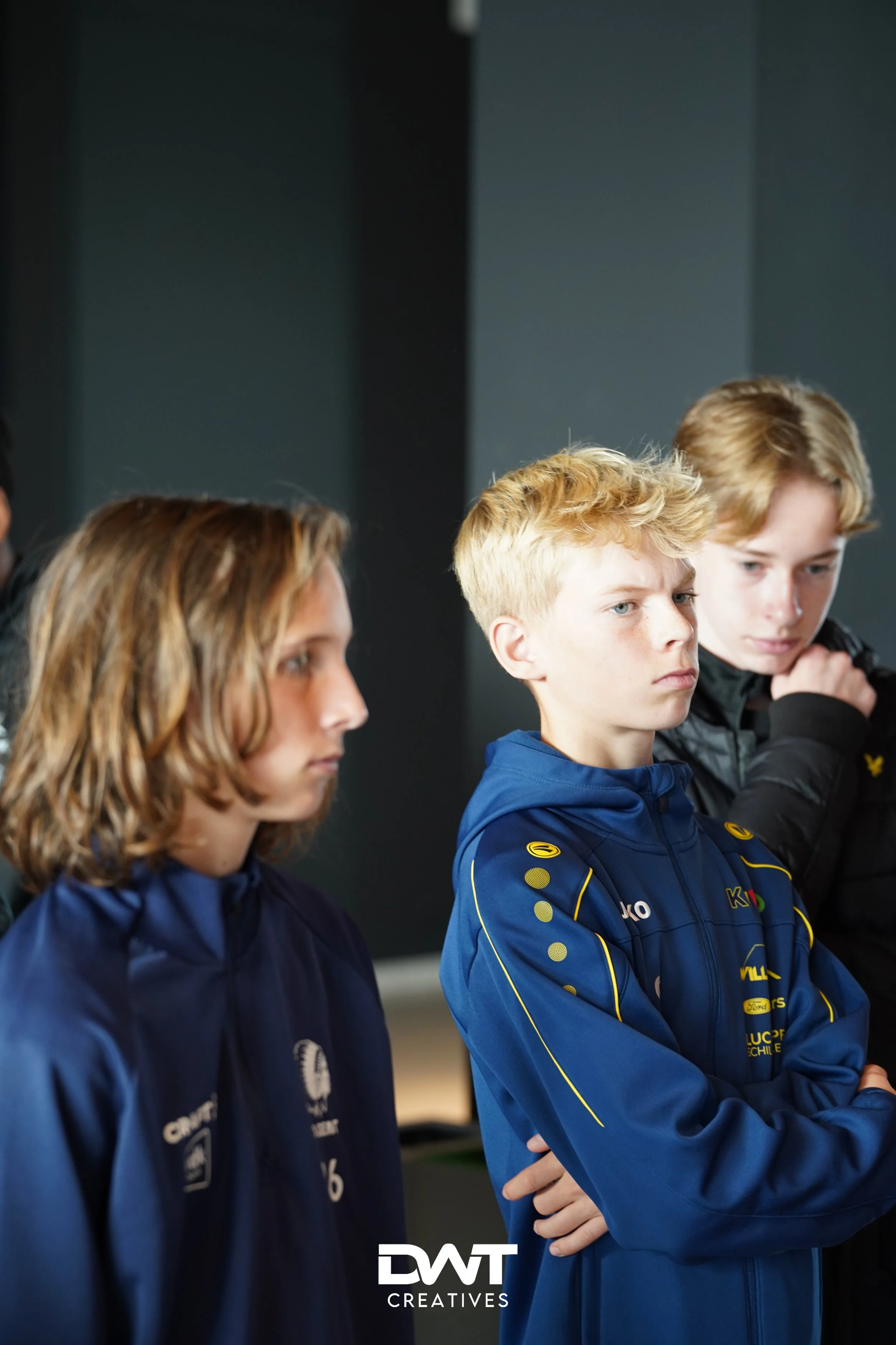 Drie tienerjongens in sportieve kleding, mogelijk tijdens een sportevenement of teamactiviteit.