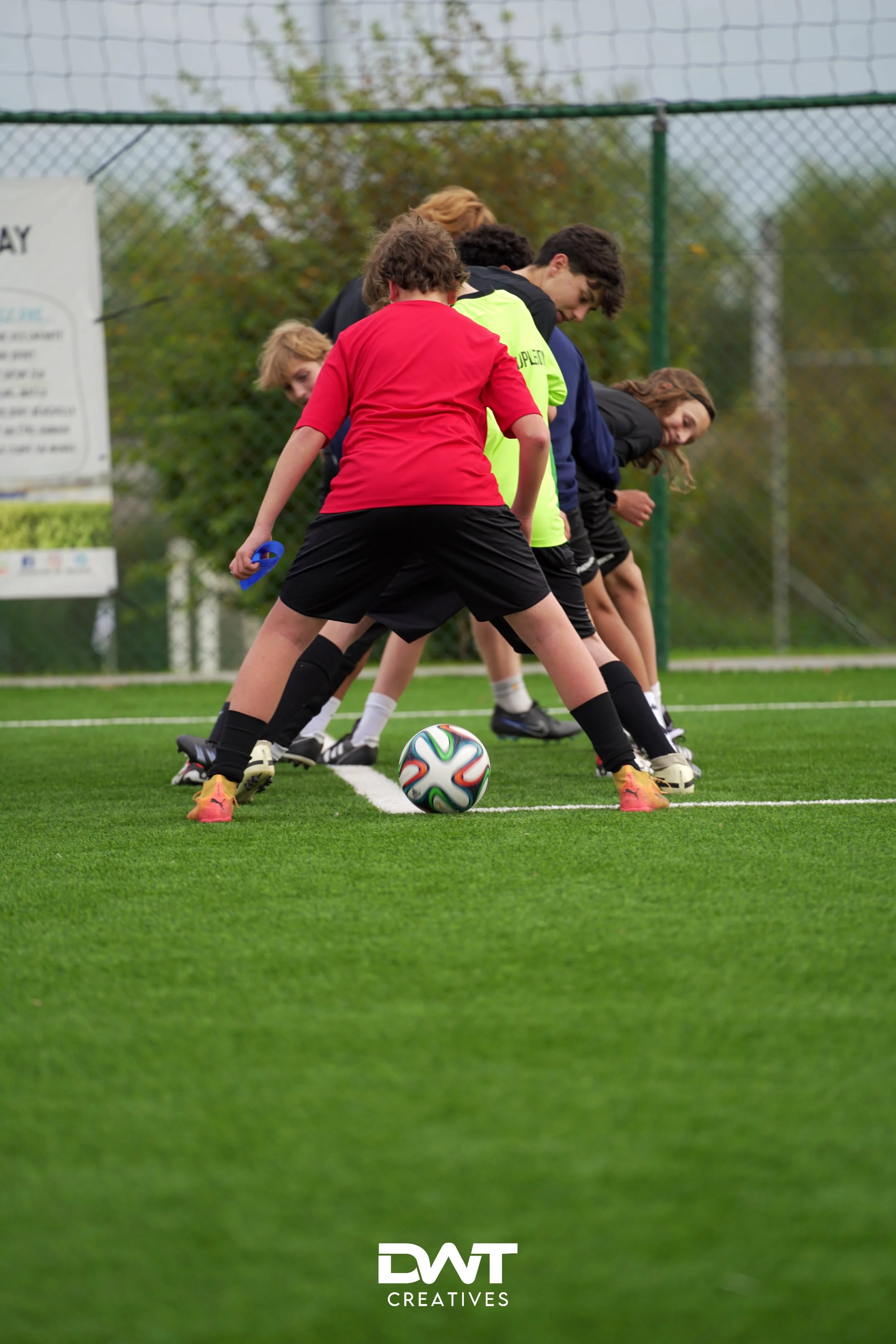 Kinderen spelen voetbal op een grasveld, met een focus op de bal en de benen van de spelers.