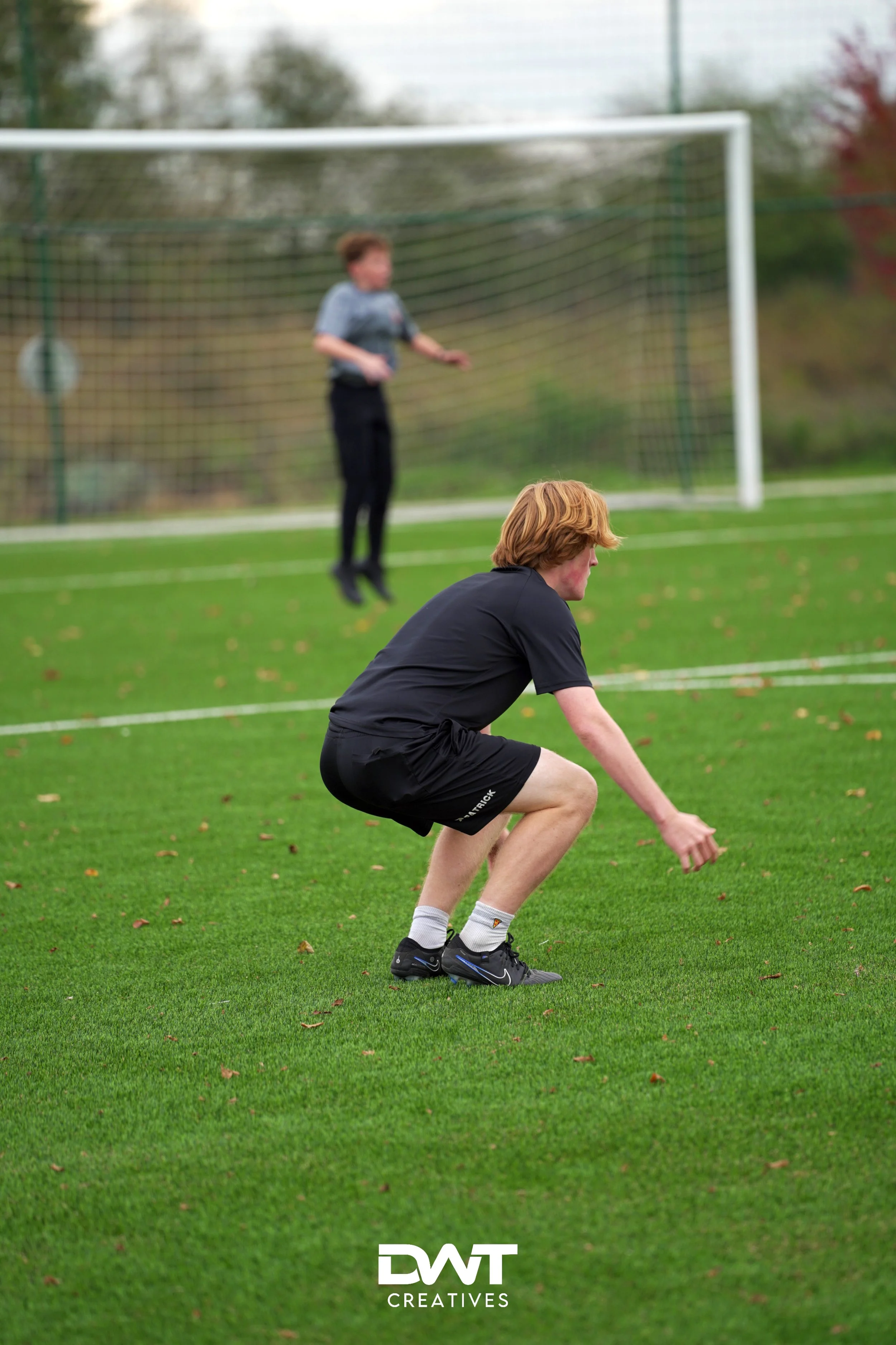 Twee jonge mannen doen fitnessoefeningen op een voetbalveld.