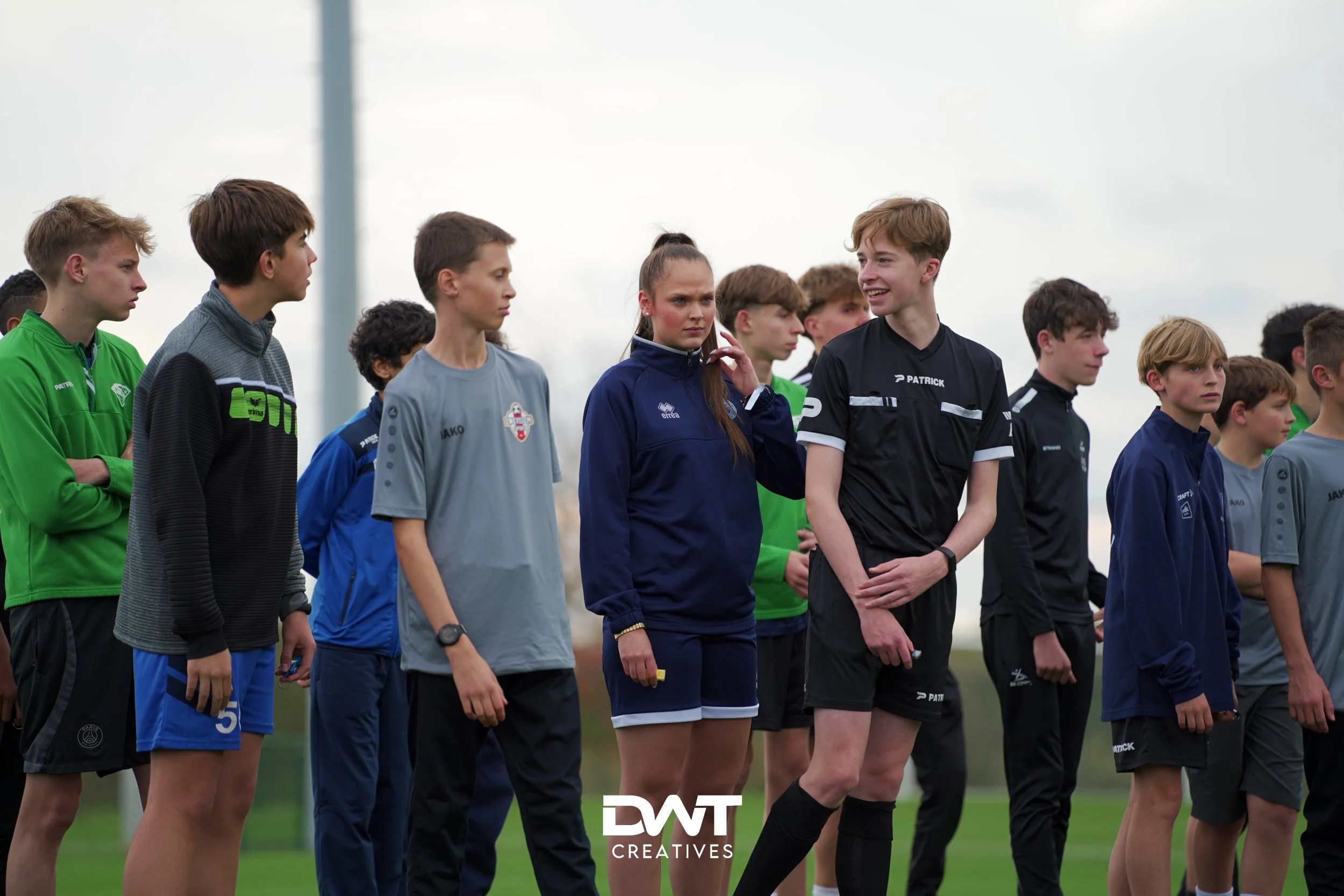 Groep jonge voetballers in sportkleding op een veld, klaar om te trainen.