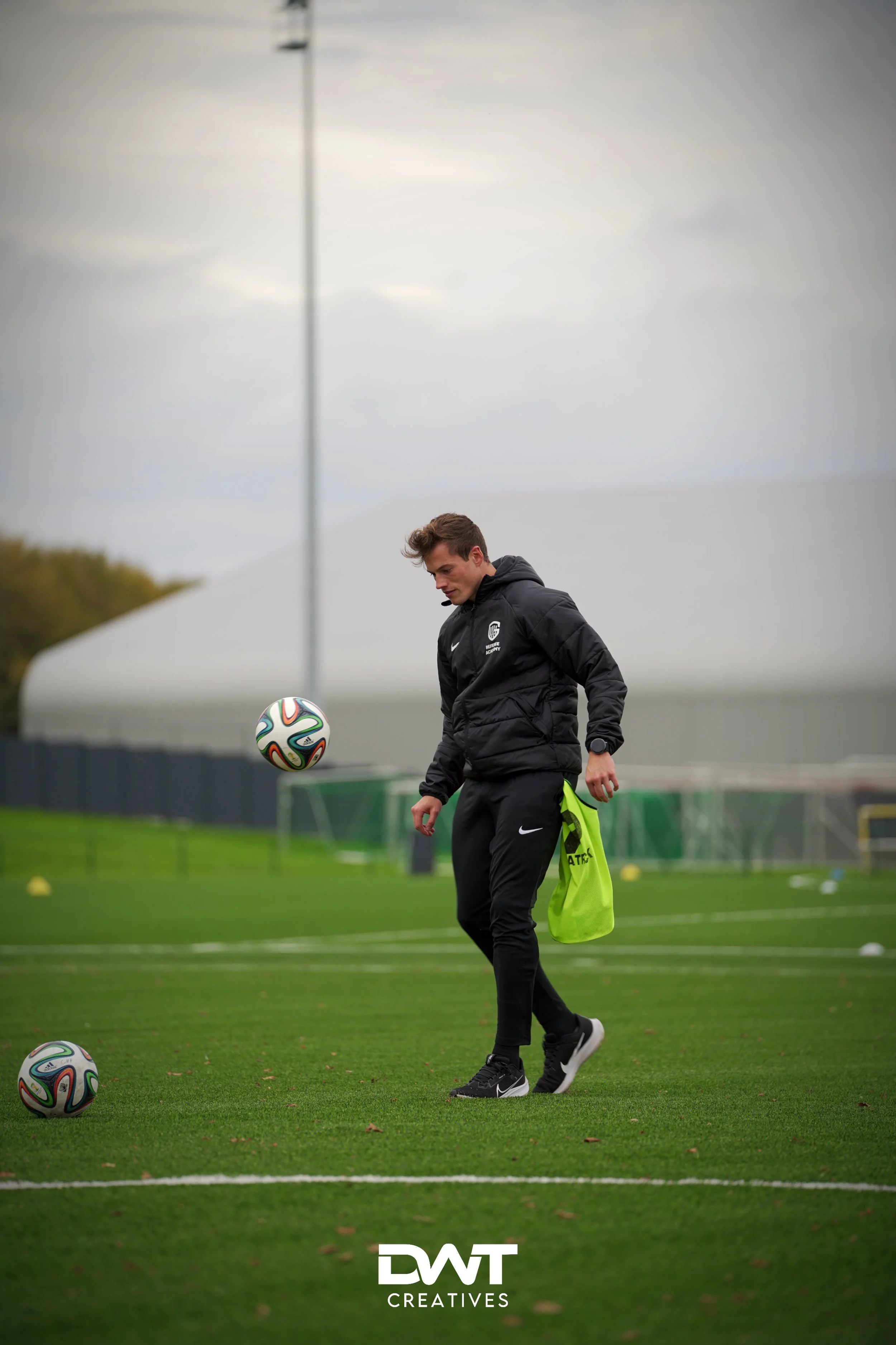 Man op voetbalveld met bal en sportkleding.