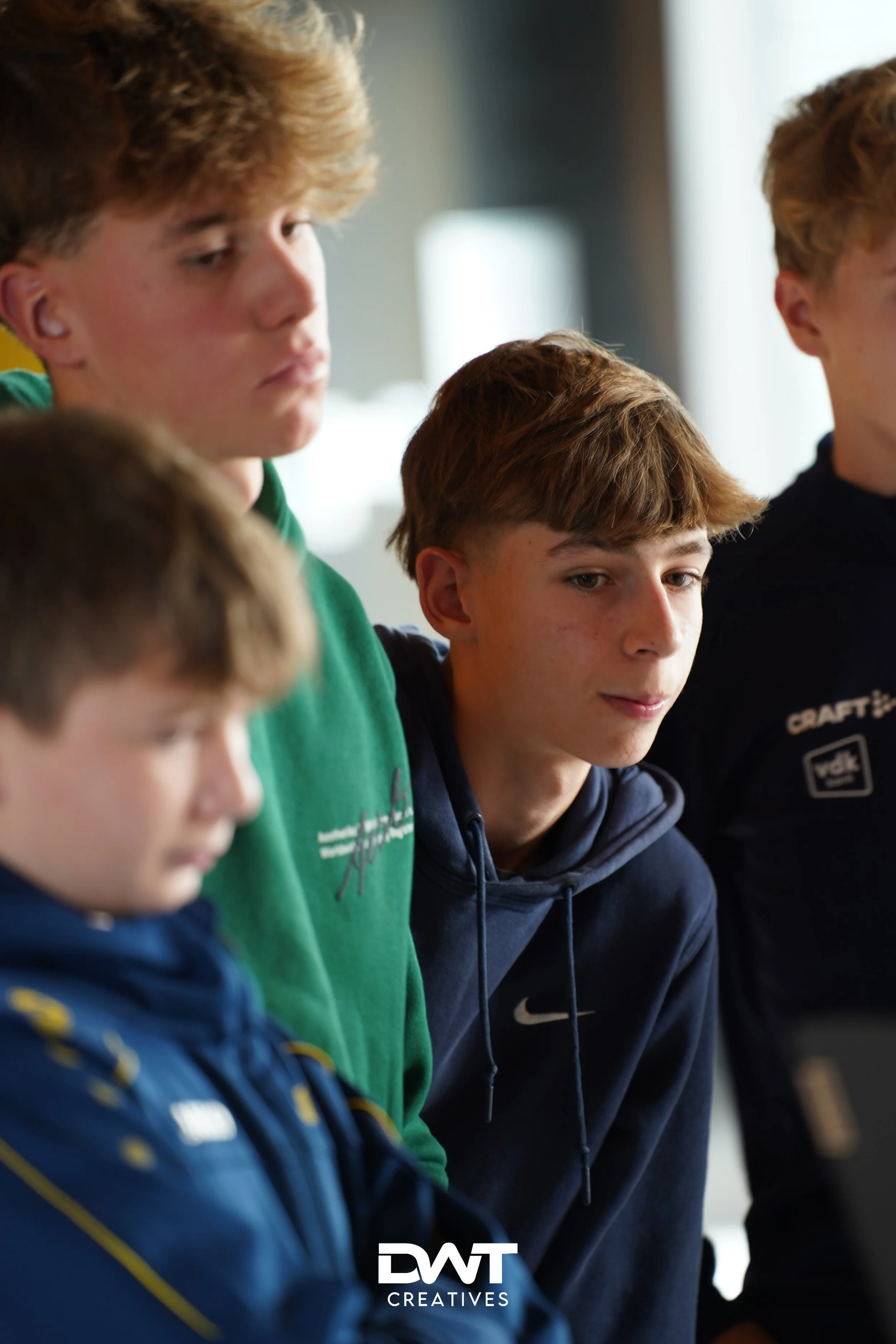 Vier jonge mensen in sportkleding, gefocust op iets buiten beeld.