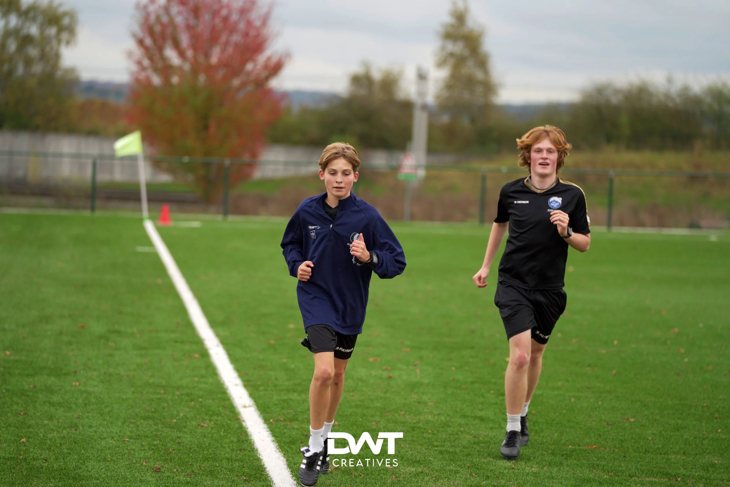 Twee tieners rennen op een voetbalveld.
