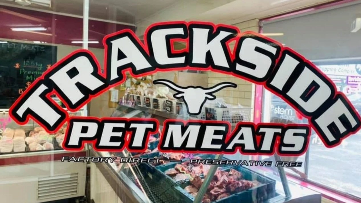 Sign for Transcontinental Pet Meats with a longhorn skull logo, indicating factory direct and preservative-free pet meats, inside a pet store