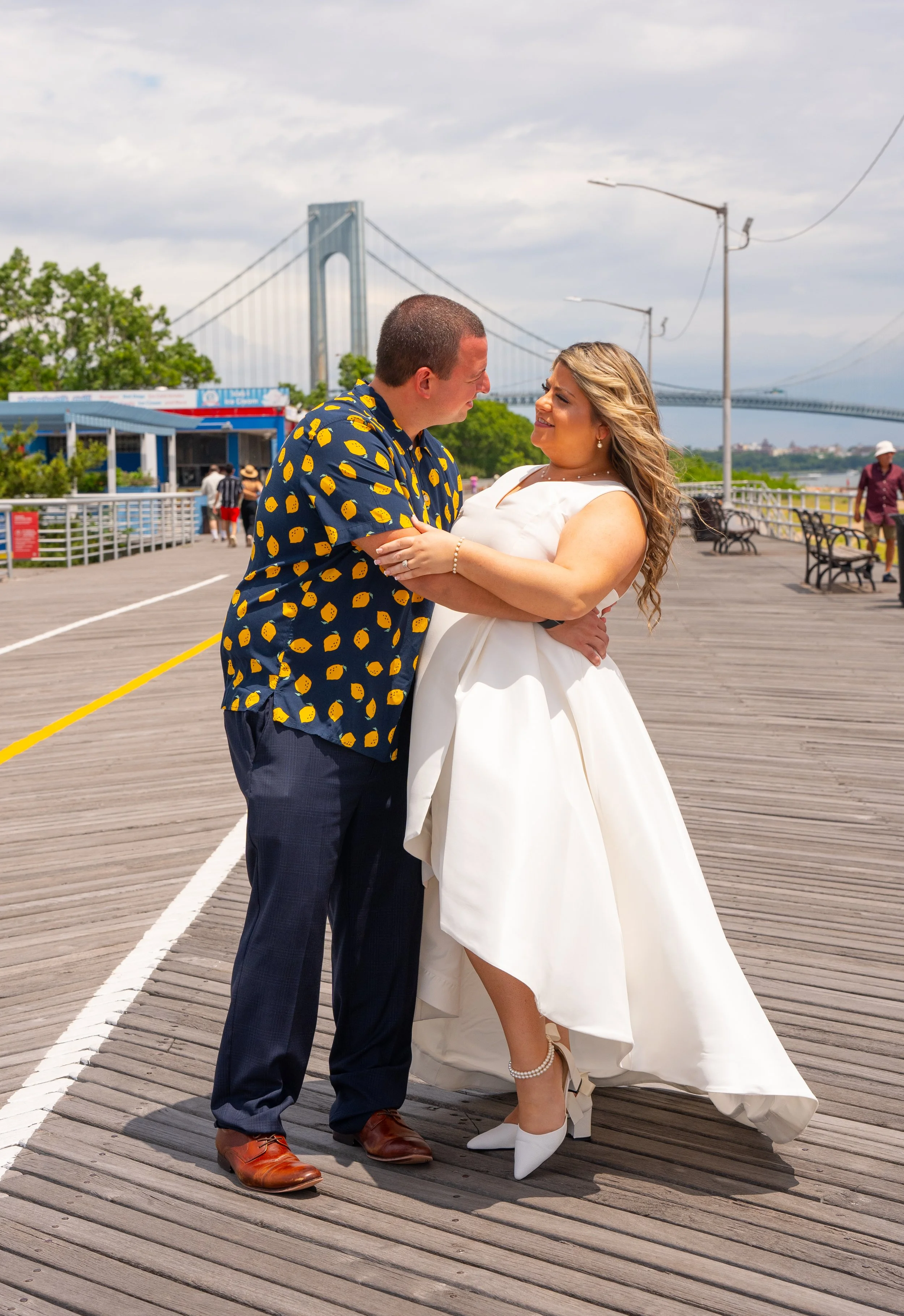 Couple embracing on boardwalk with bridge in background