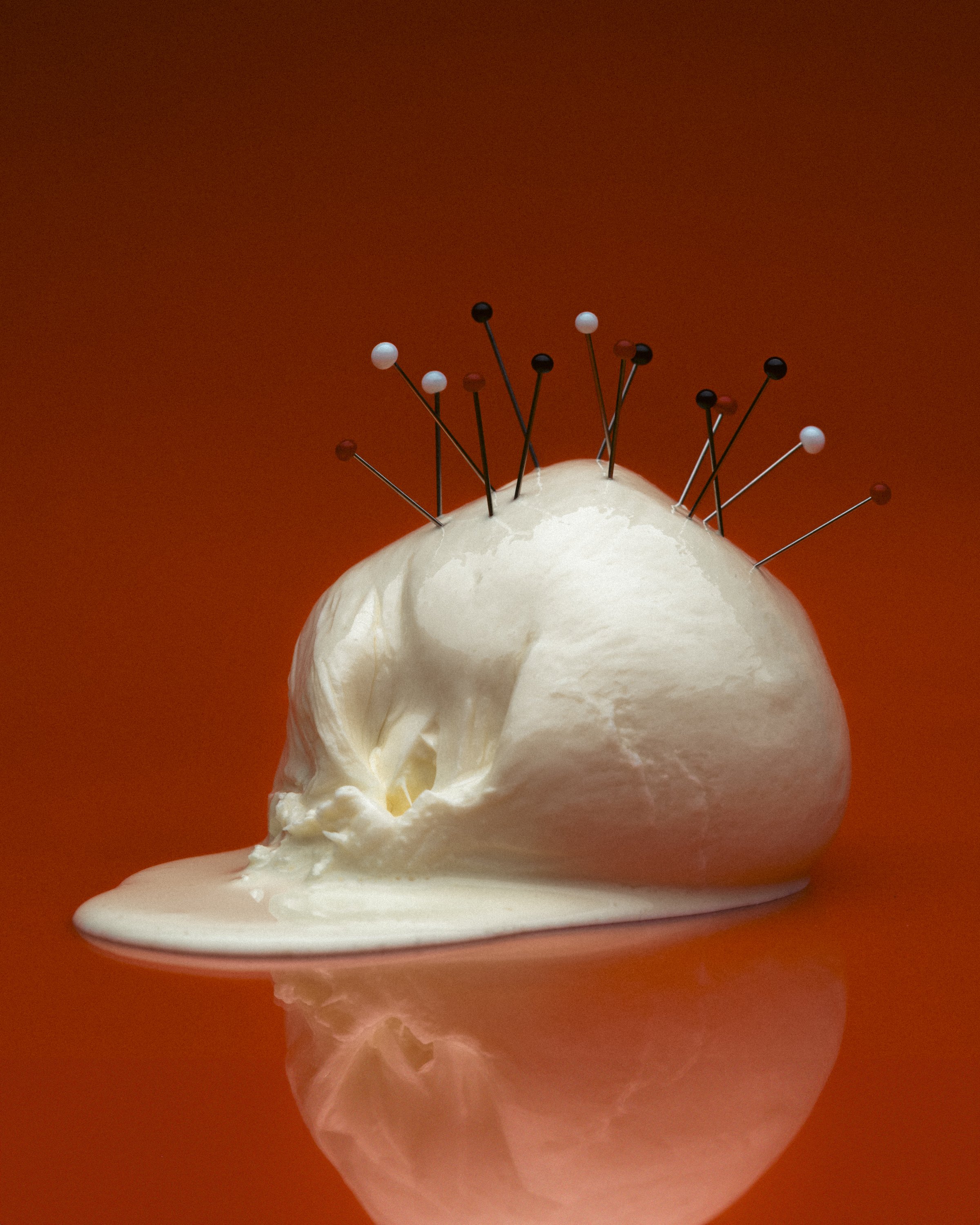 A white foam-like substance resembling a skull with pins stuck in it on an orange background.