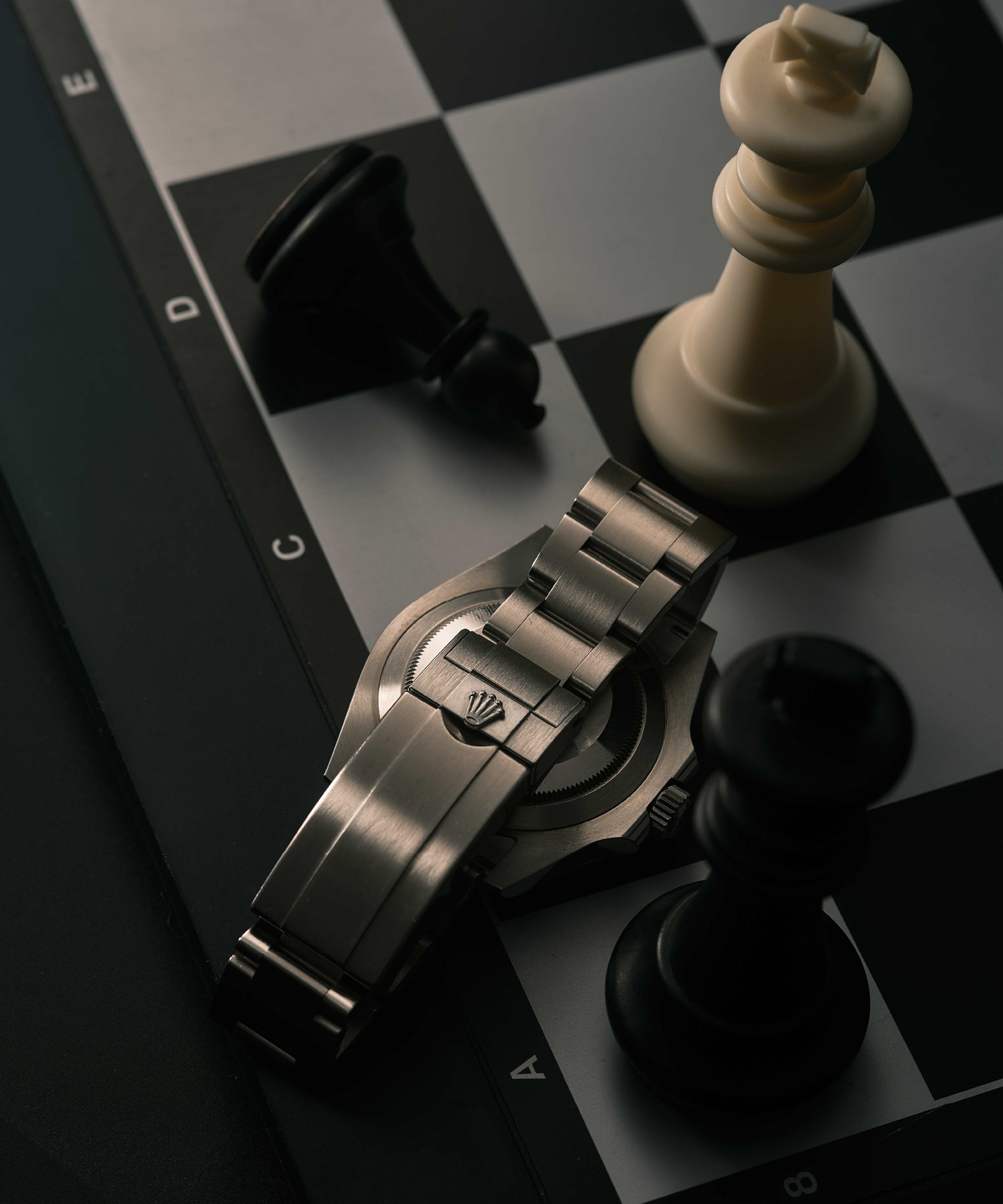 Chessboard with a watch and chess pieces, including a white king and black pawns.