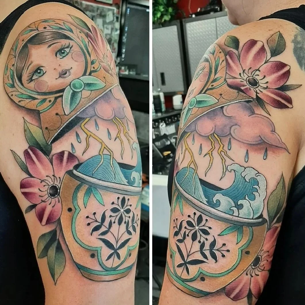 What a beautiful piece of artwork done by @korynnwesttattoo🪆A stylized nesting doll opens to reveal an inner scene of storm clouds, lightning, and waves, framed by florals. 🌸 The mix of soft pastels and bold linework highlights contrast, calm on th