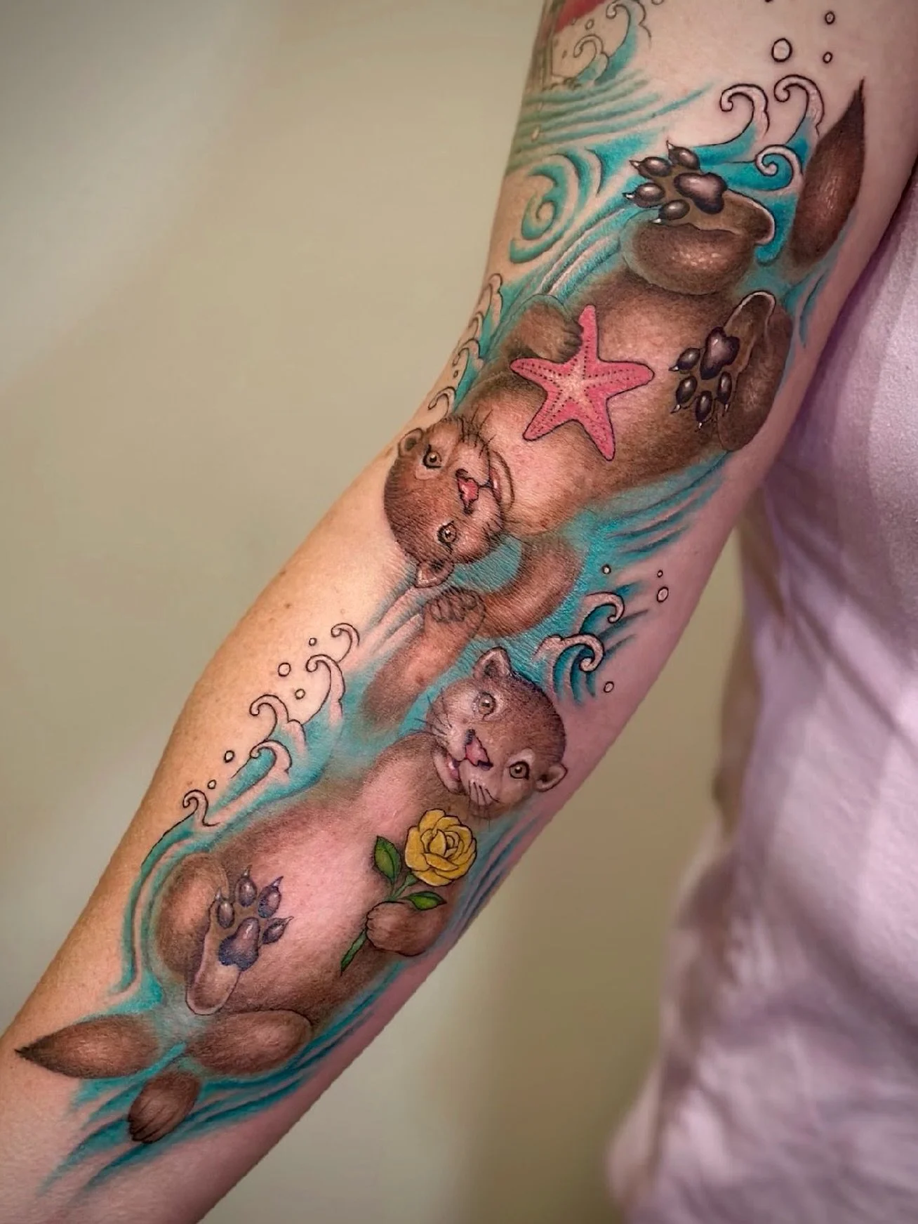 @selinatat2 created this dreamy little otter duo 🦦✨ Floating through turquoise waves with a starfish and a yellow rose, these two turned into the sweetest arm piece adventure. #otters #wildlife #socute #tattoo #artist