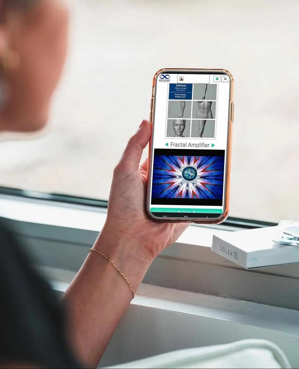Person holding a smartphone with a health or fitness app open, displaying a body diagram, fractal image, and text. SEFI technology programmable micro dots
