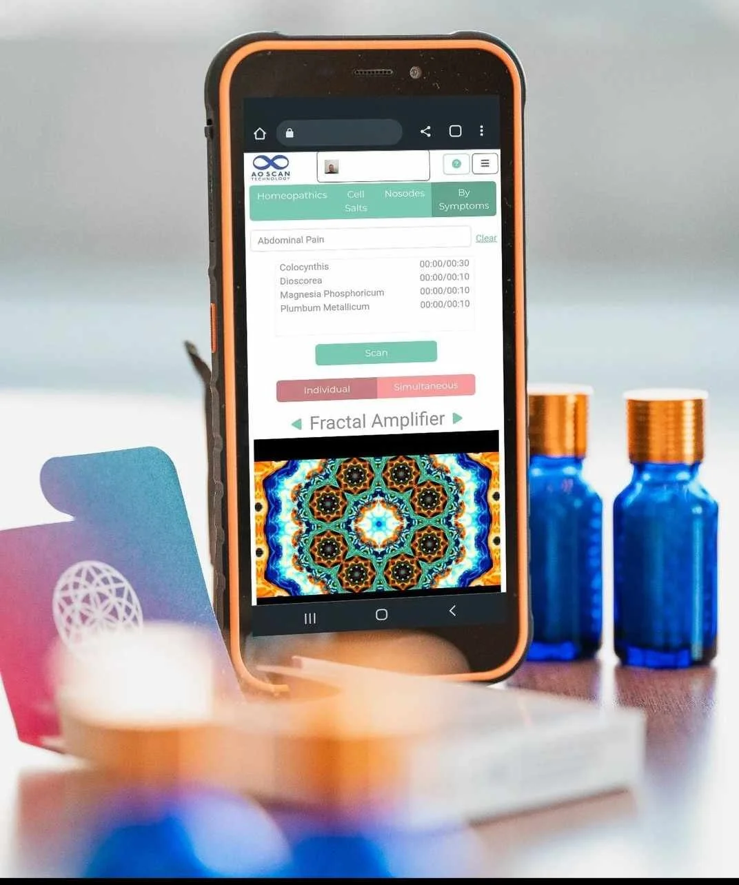 Smartphone displaying an app for homeopathic remedies, with options for scan modes and a colorful fractal image. AO scan technology