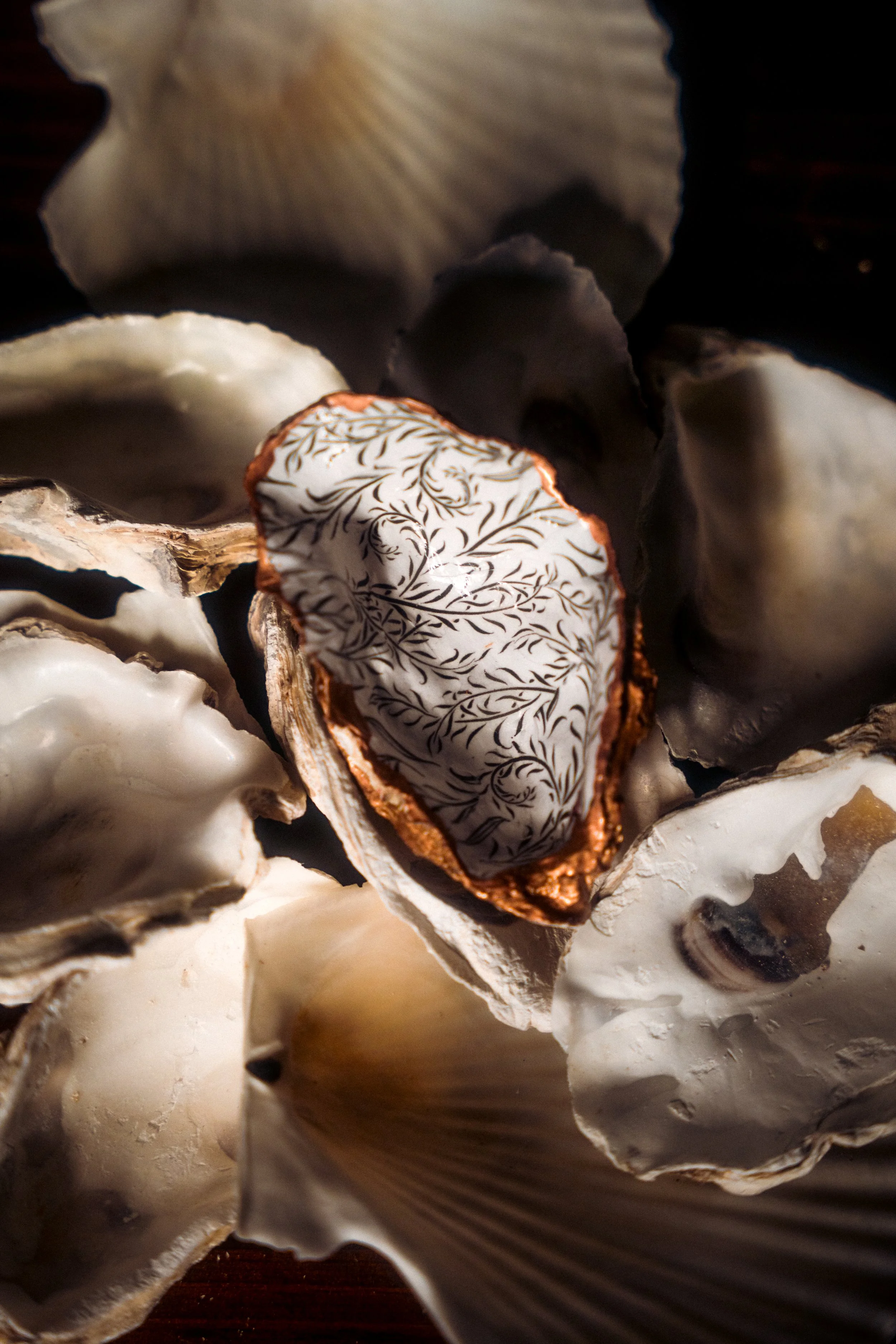 A collection of oyster shells with one shell featuring a decorative pattern on the inside.