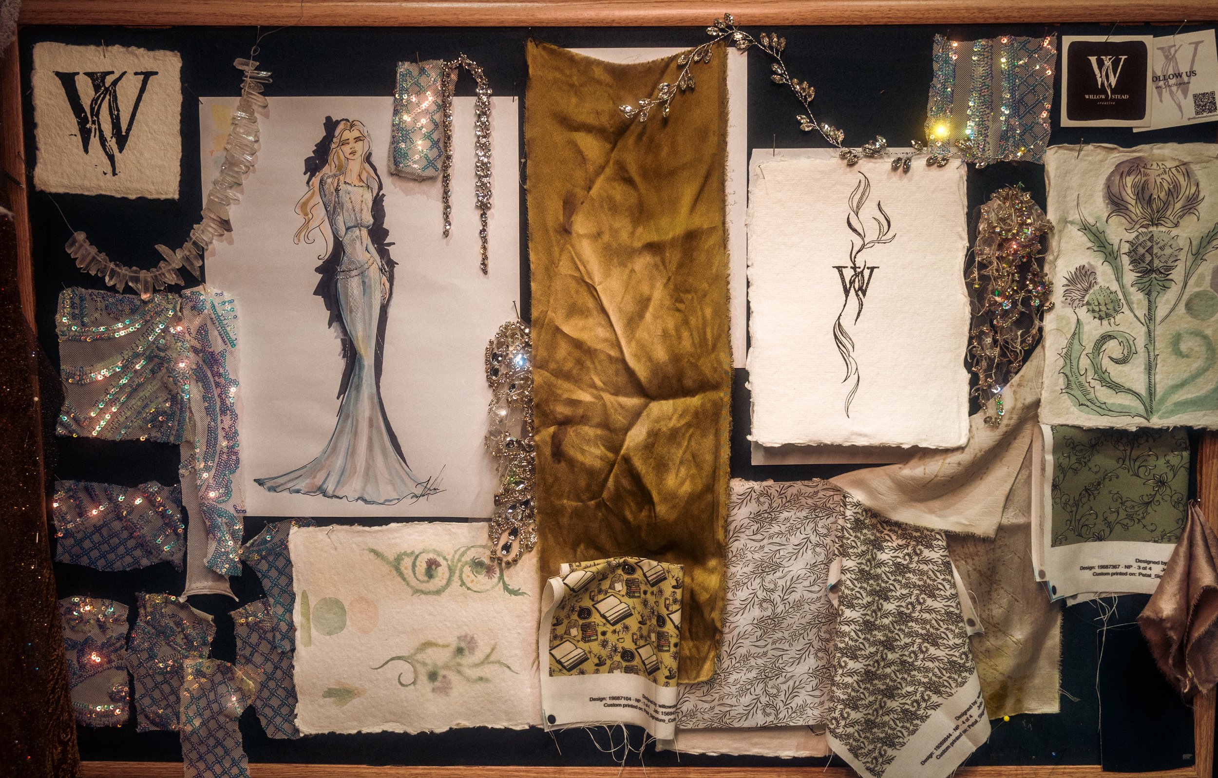 A collection of fabric samples, sketches, and decorative jewelry on a black background, featuring a central fashion illustration of a woman in a gown, rhinestone accessories, and various textured swatches.