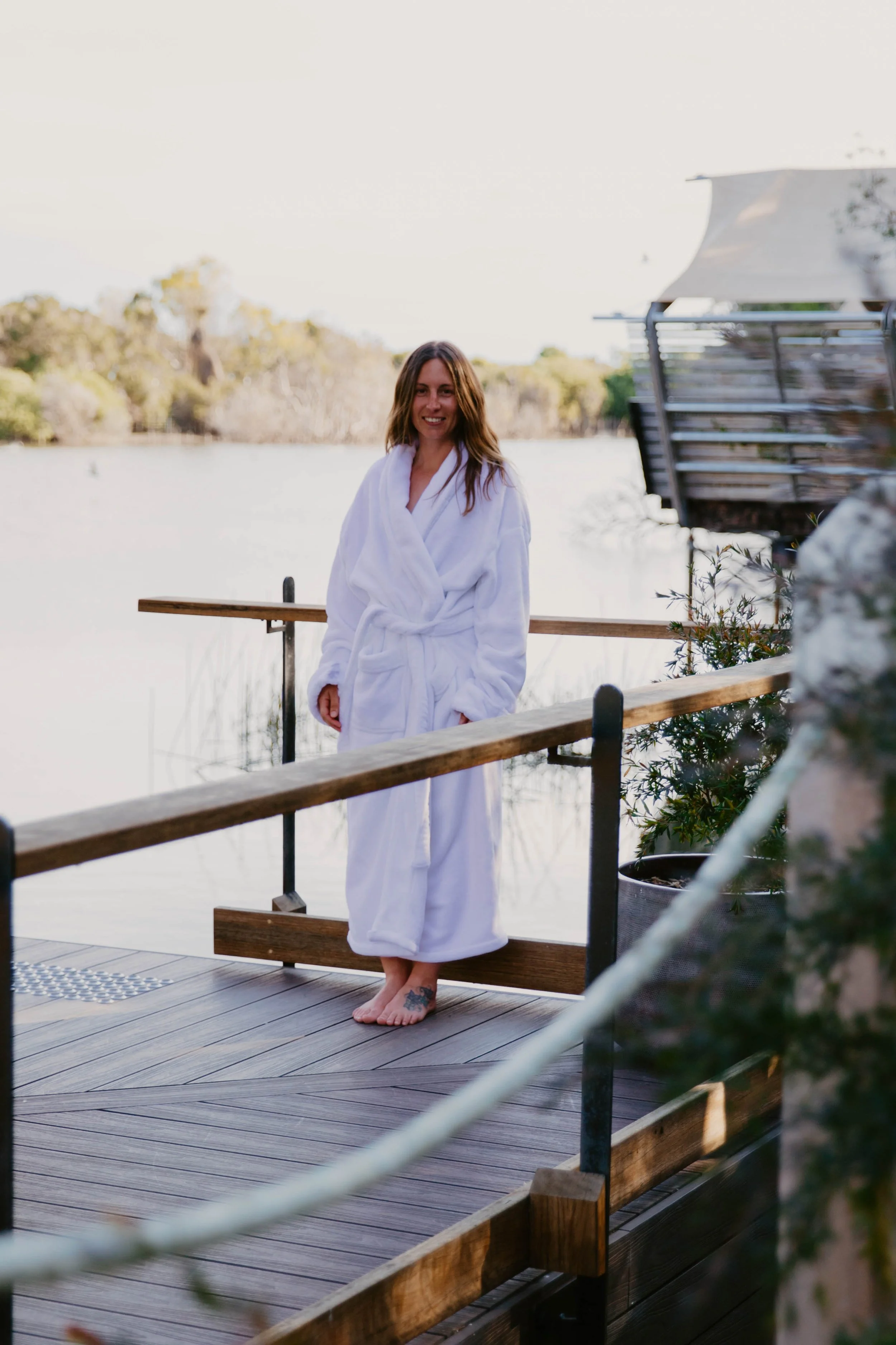 A woman smiling in a white robe towards the camera