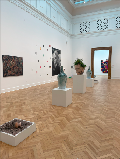 The full installation of the work, including the failed saggar experiments at either end, and two cone 10 reduction fired bottle vases on either side of the centerpiece.