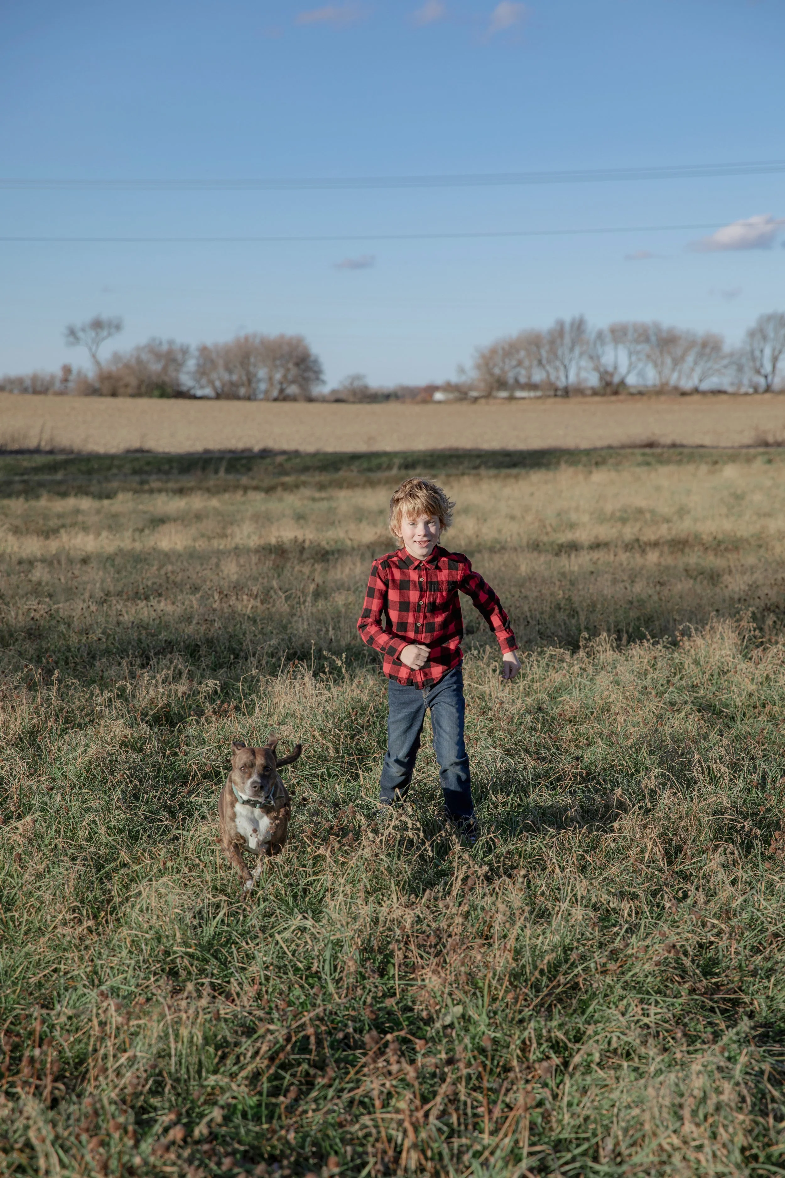 Picture of a boy running through a field with his dog