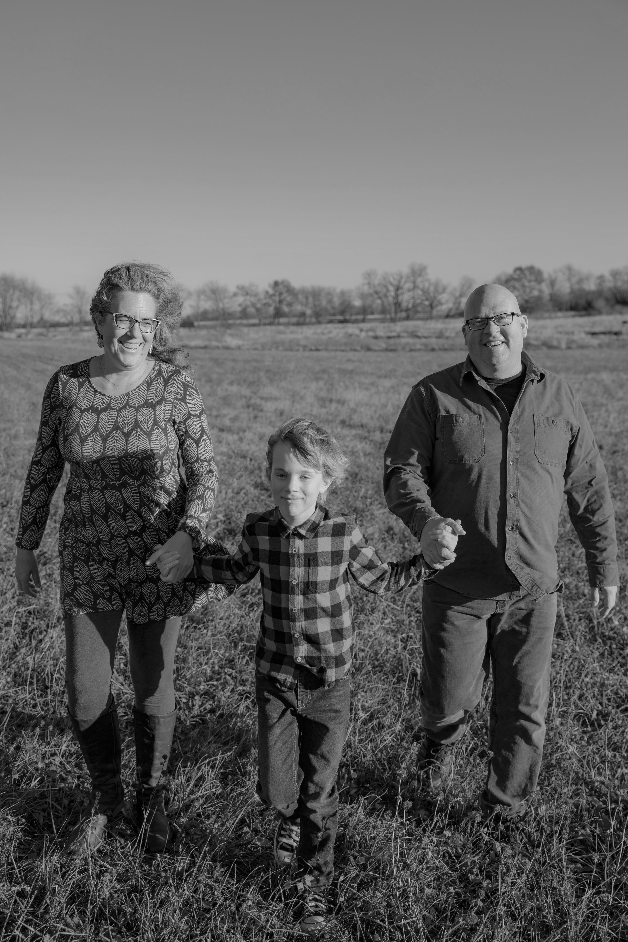Picture of a family laughing, walking and holding hands through a field 