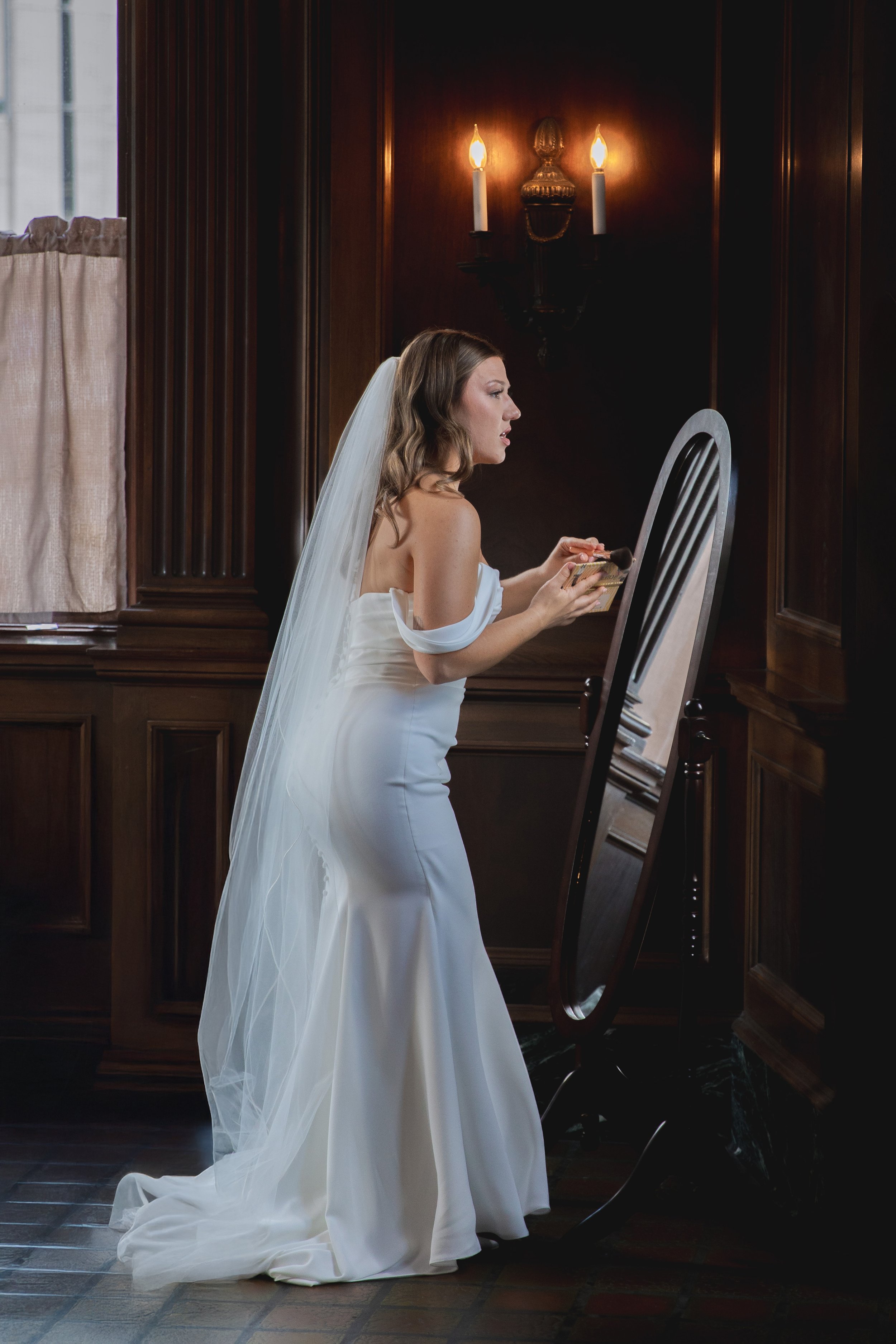 Bride touching up her makeup in the mirror