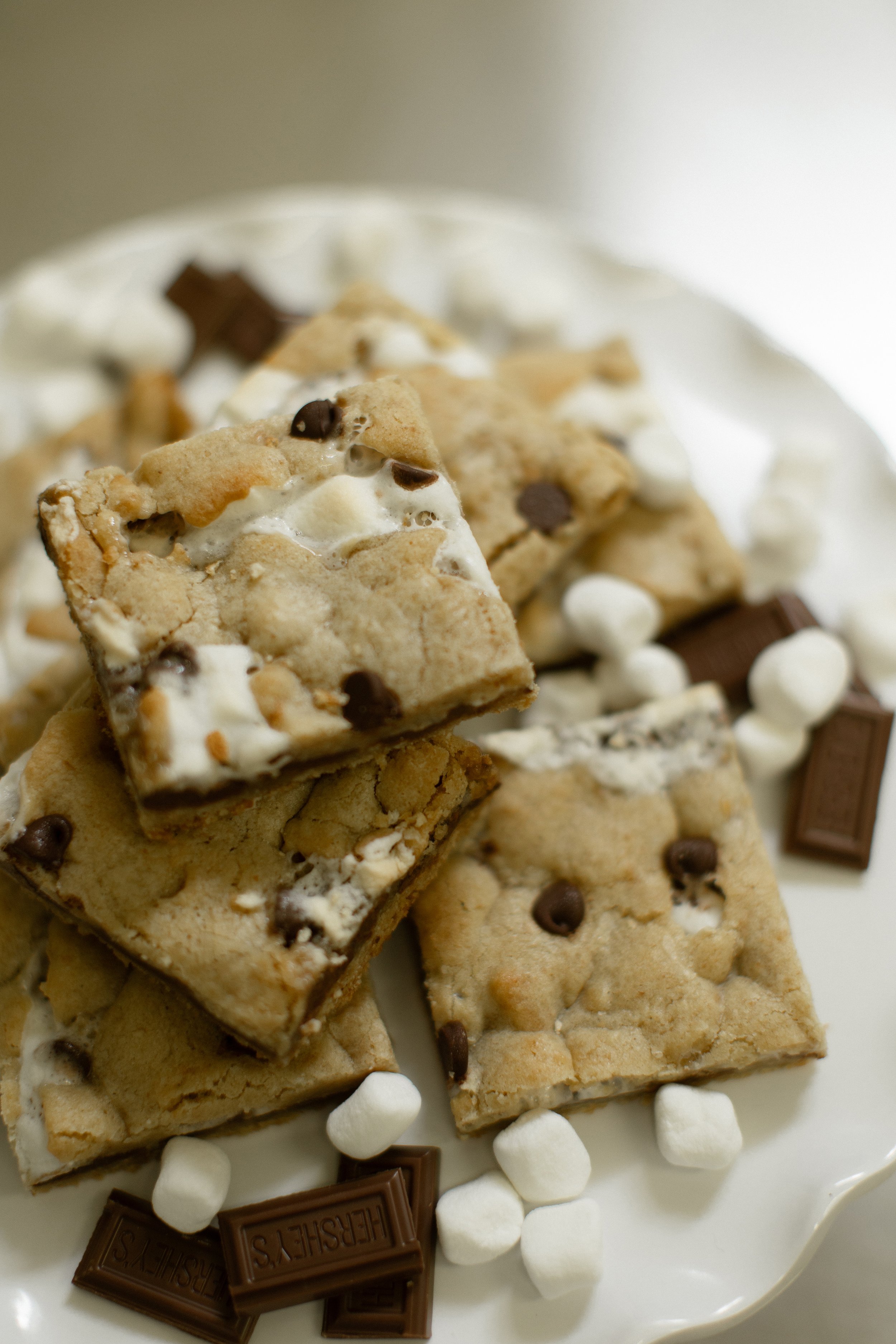 S'mores bars with chocolate chips, marshmallows, and chocolate pieces on a plate.