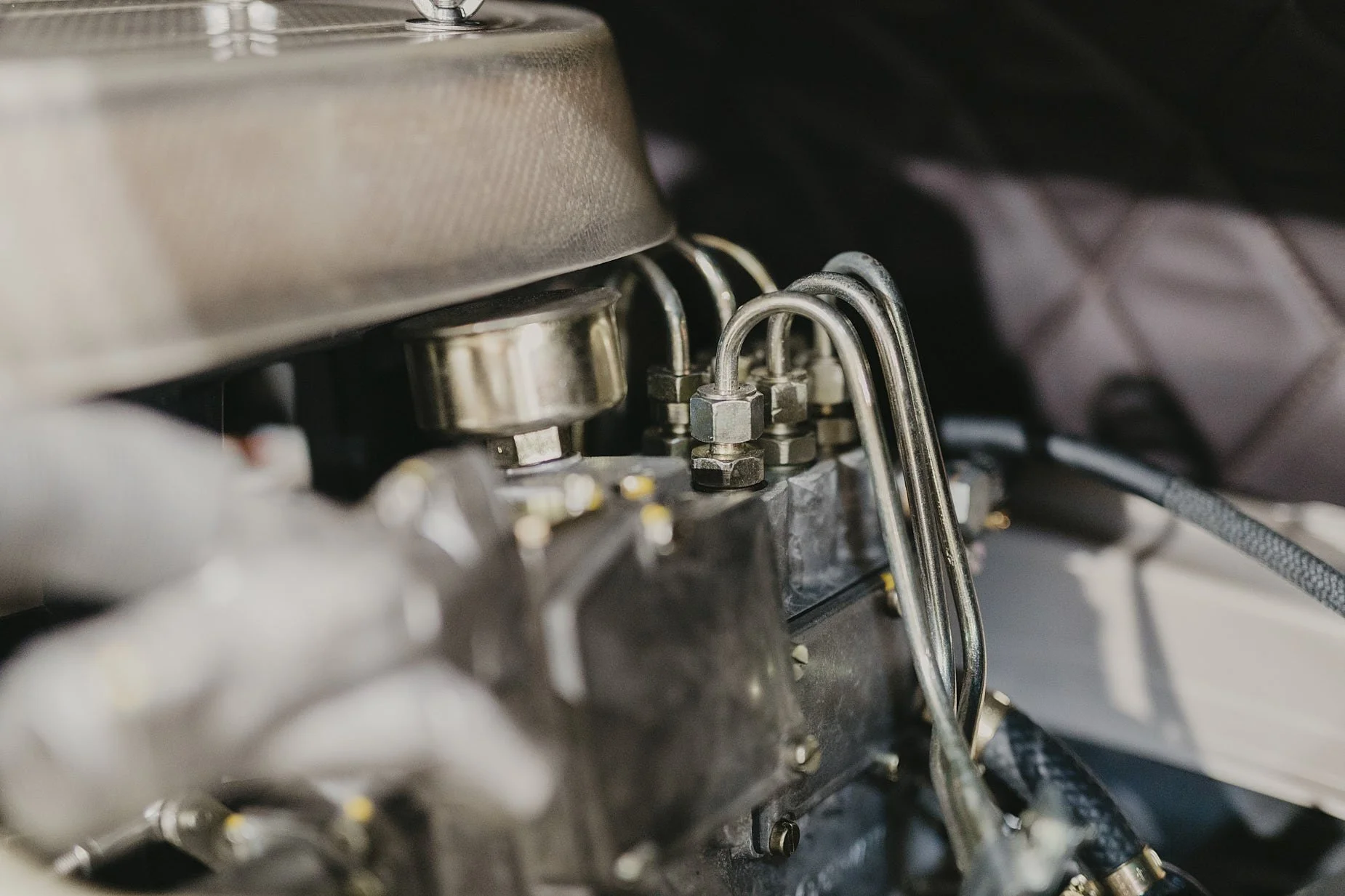 Close-up of a Porsche mechanical engine component with metal pipes and fittings.