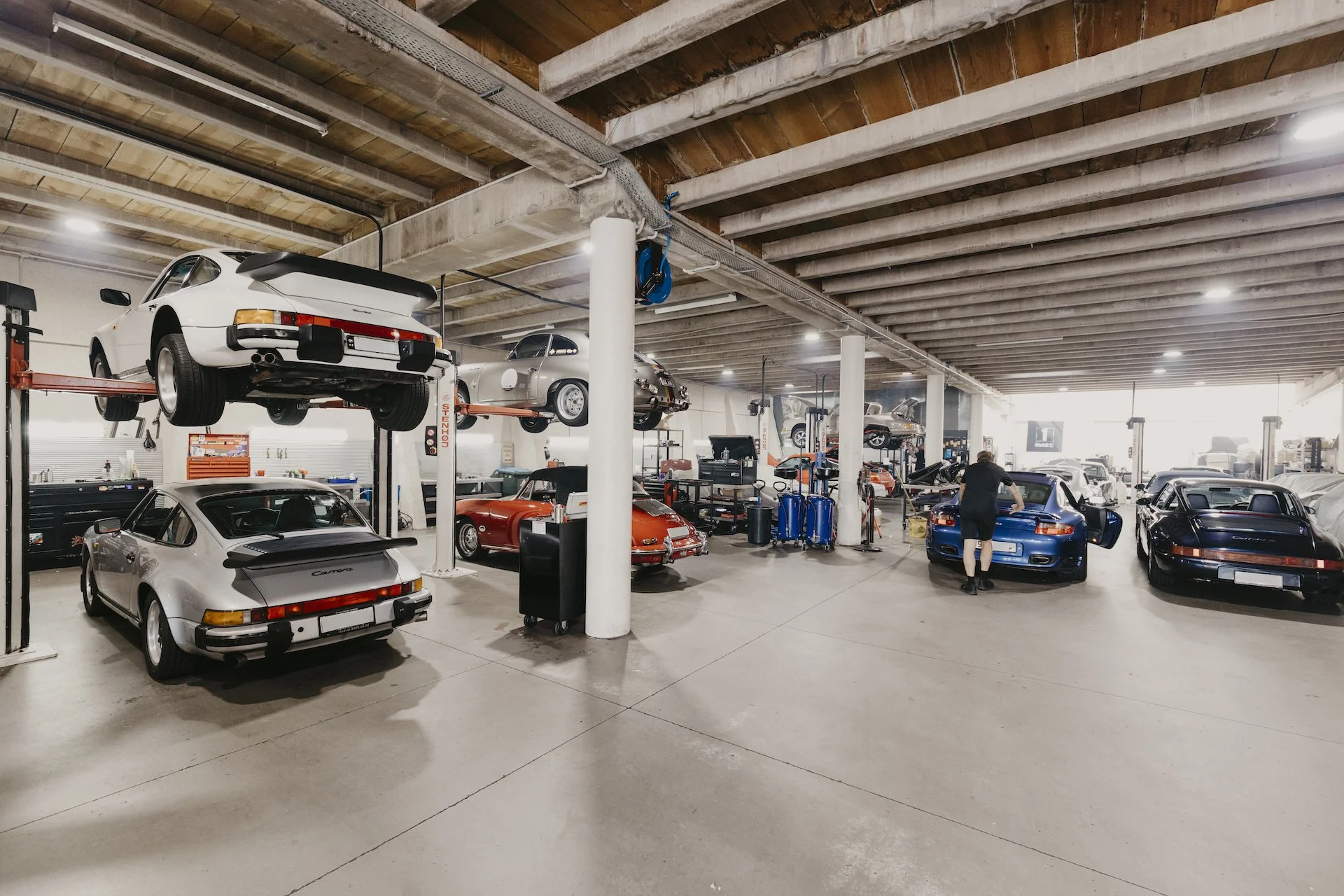 Inside the Motorscience workshop in Grey Lynn, a tidy and large space with multiple classic and modern Porsche cars, some on lifts.