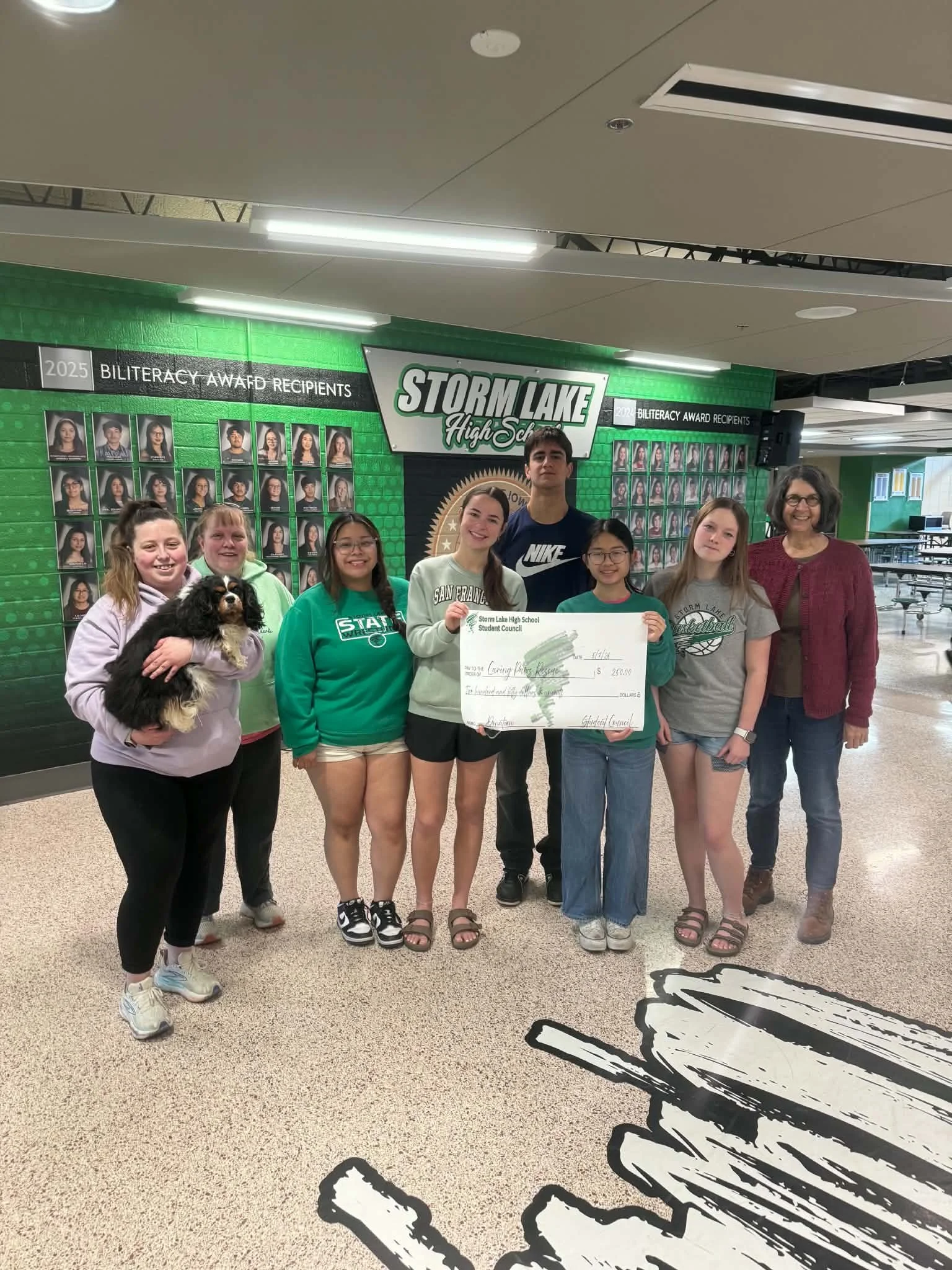 CPR member Hailey, holding Dolly, (left), Kim (2nd in from left) and Dolores (far right) collect a donated check SLHS students!