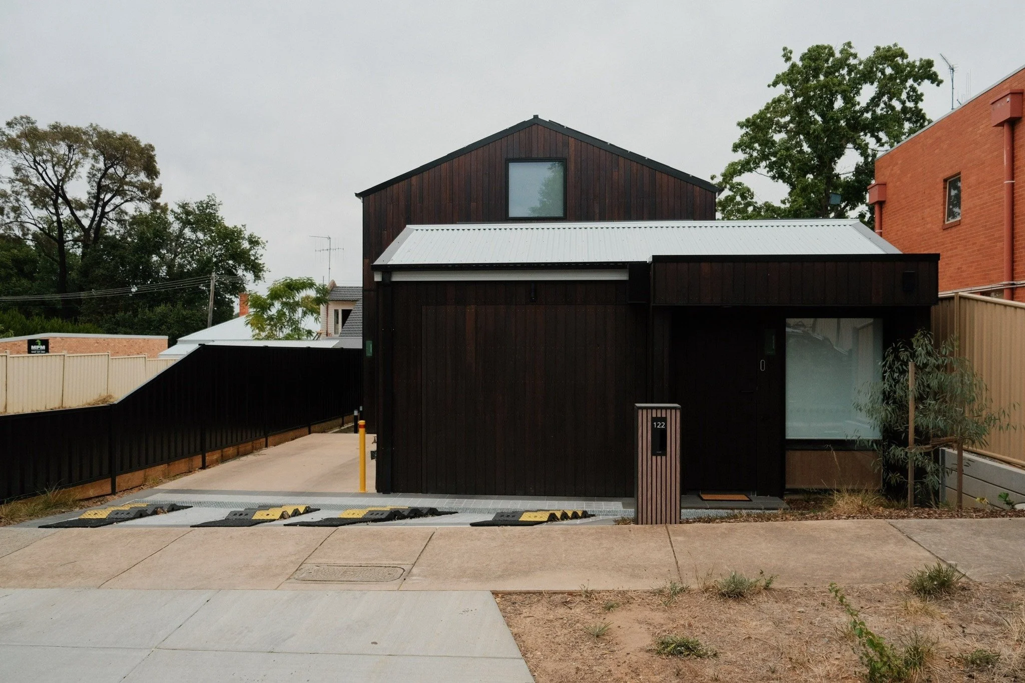 Garage door — New build, custom flush mount tilt door with timber cladding matched to exterior of the home