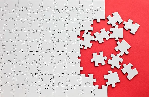 White jigsaw puzzle with missing pieces on a red background.