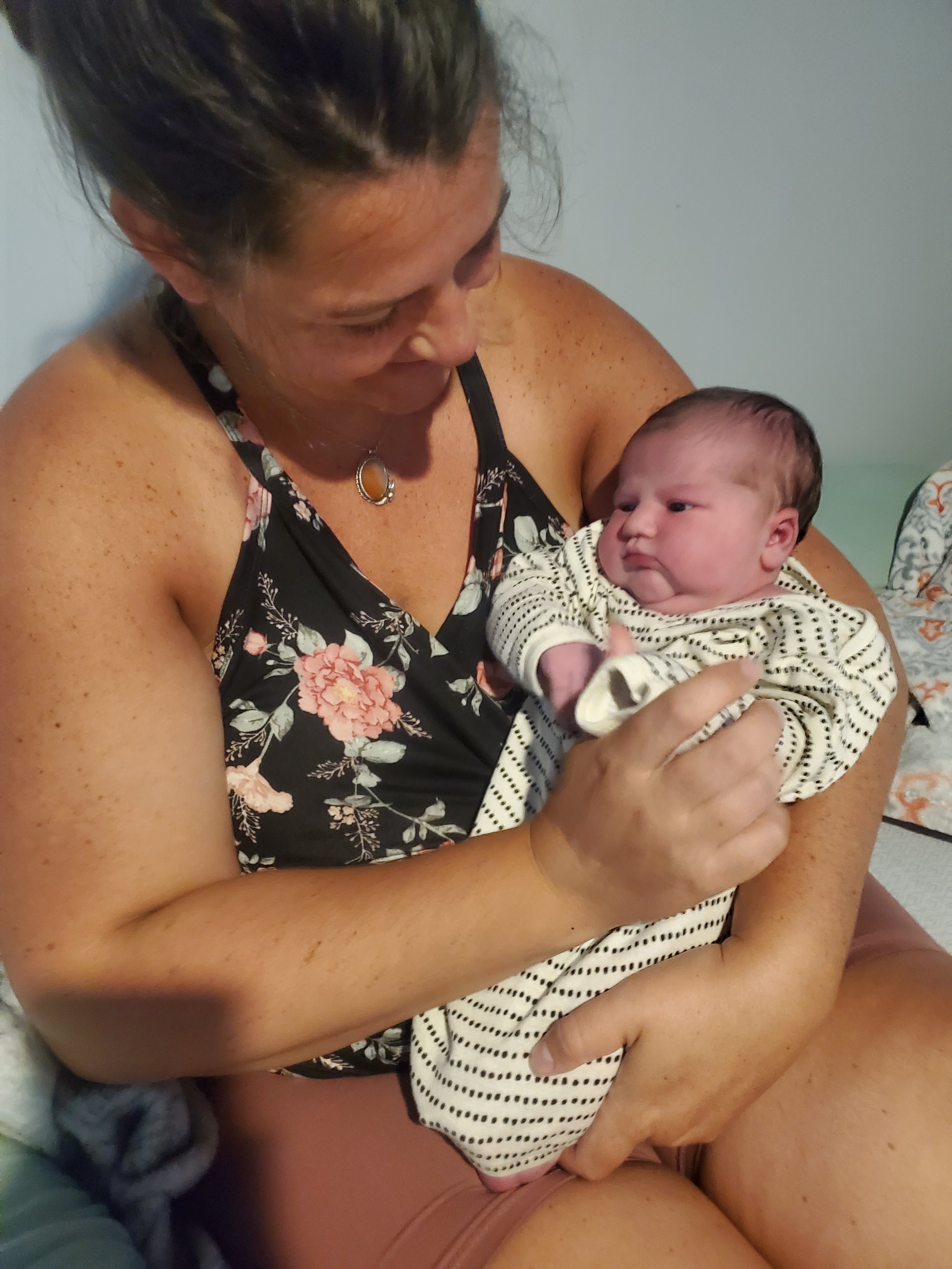 Postpartum mama happily shows off her sweet baby girl