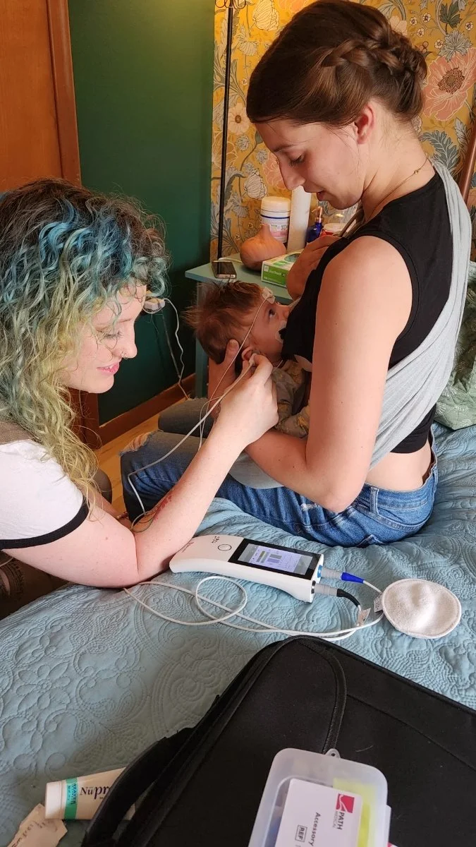 Baby breastfeeding while getting hearing screening