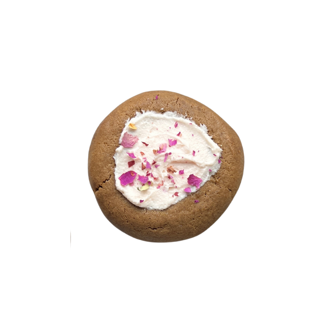 Gingerbread cookie topped with rose cream cheese frosting and dried rose petals for a festive, floral finish