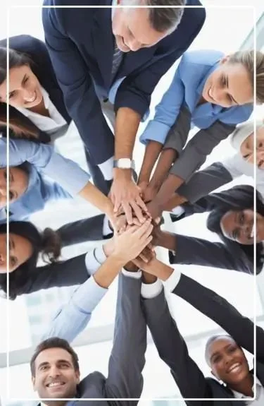 Group of diverse professionals with hands stacked in the center during a meeting.