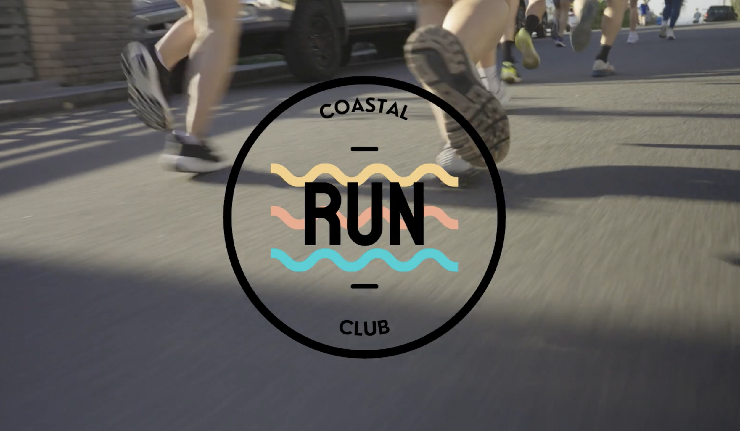 Several people running on a street during a race or marathon, with a logo in the foreground that reads 'Coastal Run Club'.