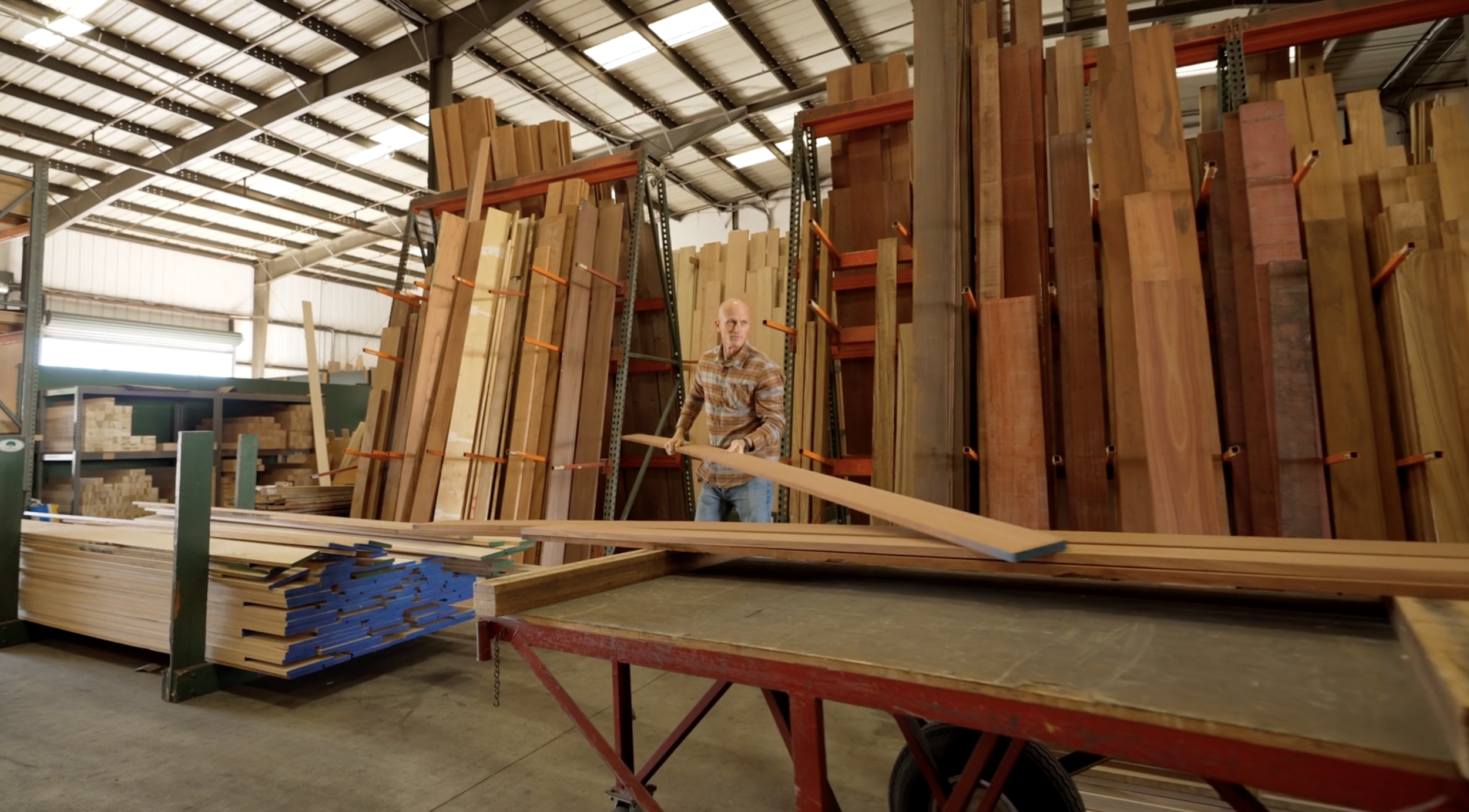Man organizing plywood sheets in a warehouse.