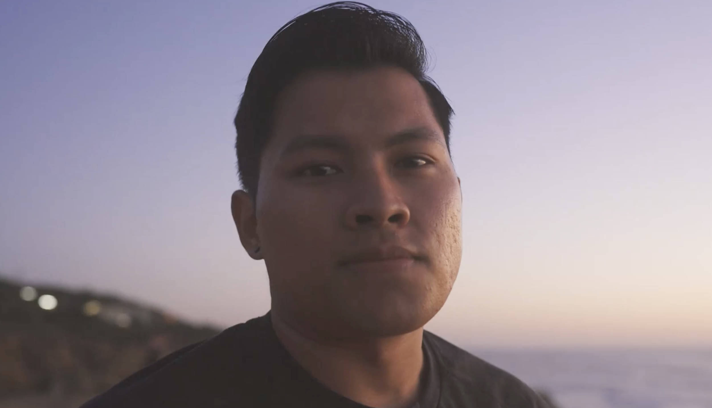 Close-up of a young man's face with a calm expression against a soft sky background
