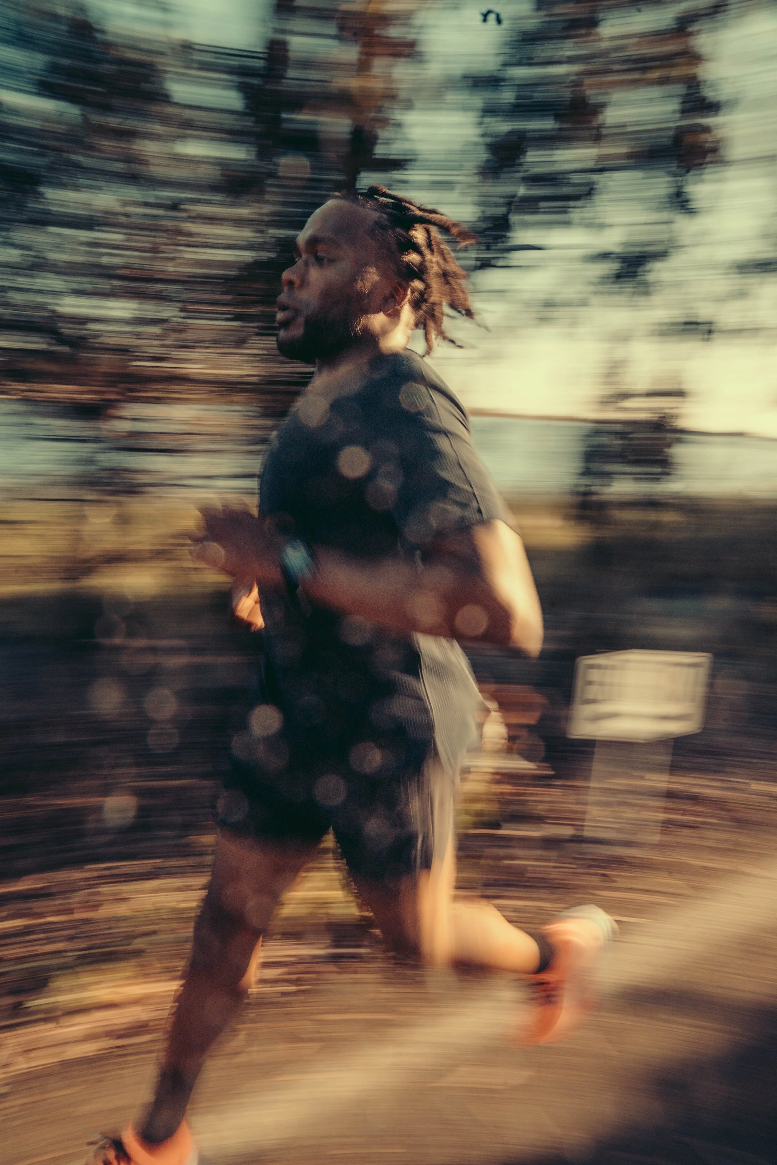 A person running outdoors during sunset, with trees in the background and motion blur