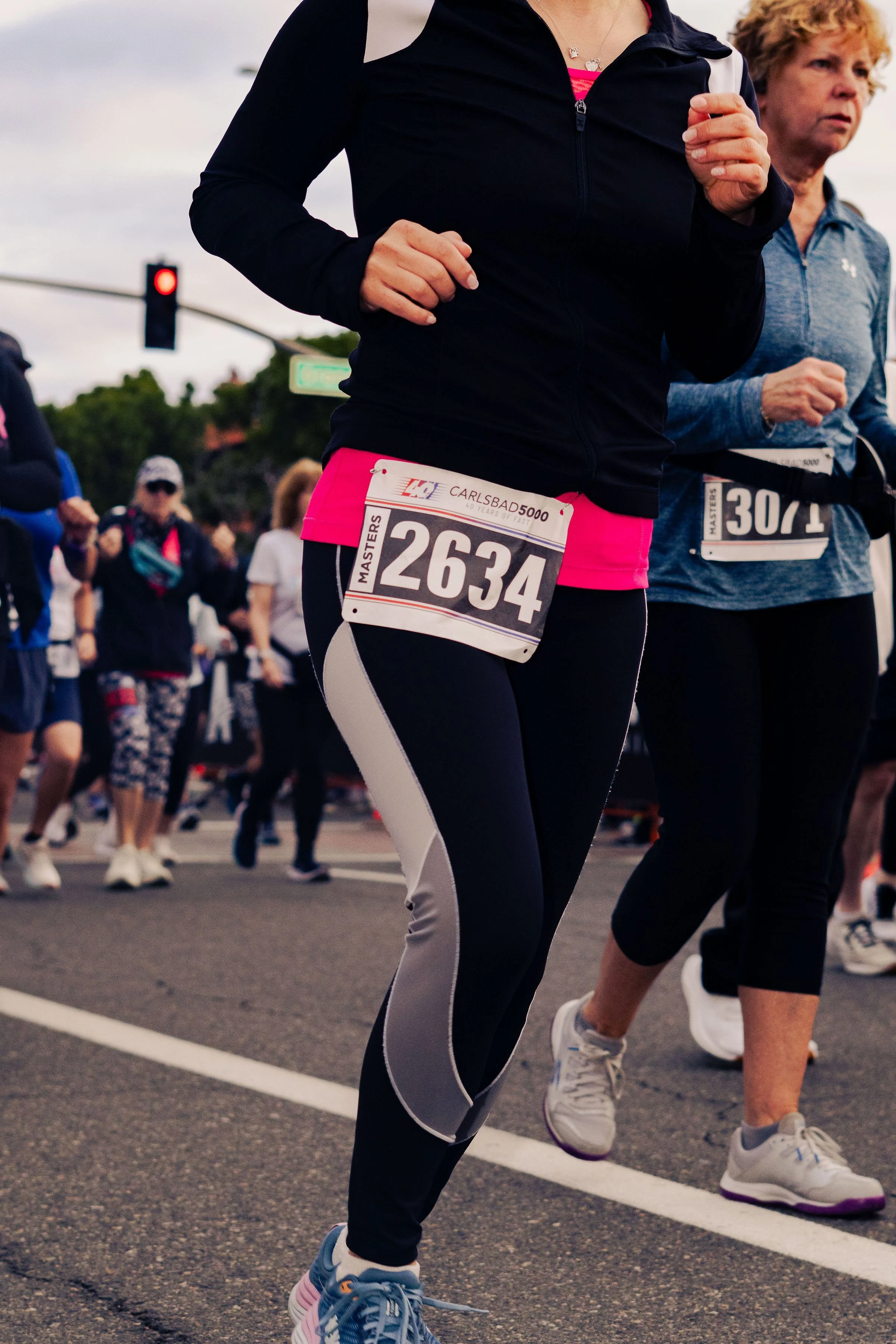 People running in a marathon or race on a city street with a crowd of spectators watching.
