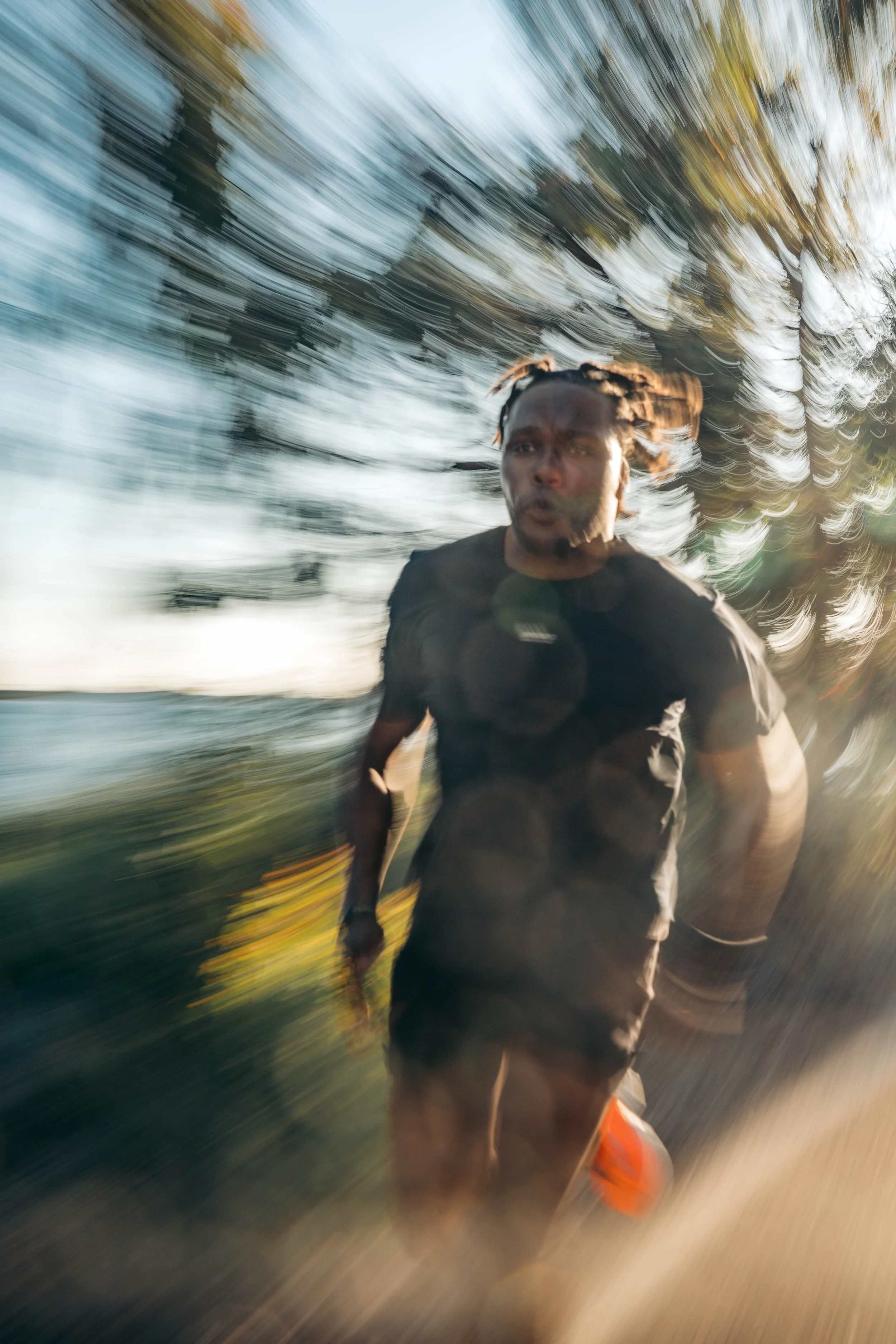 A person running outdoors with trees and sky in the background, captured with motion blur.