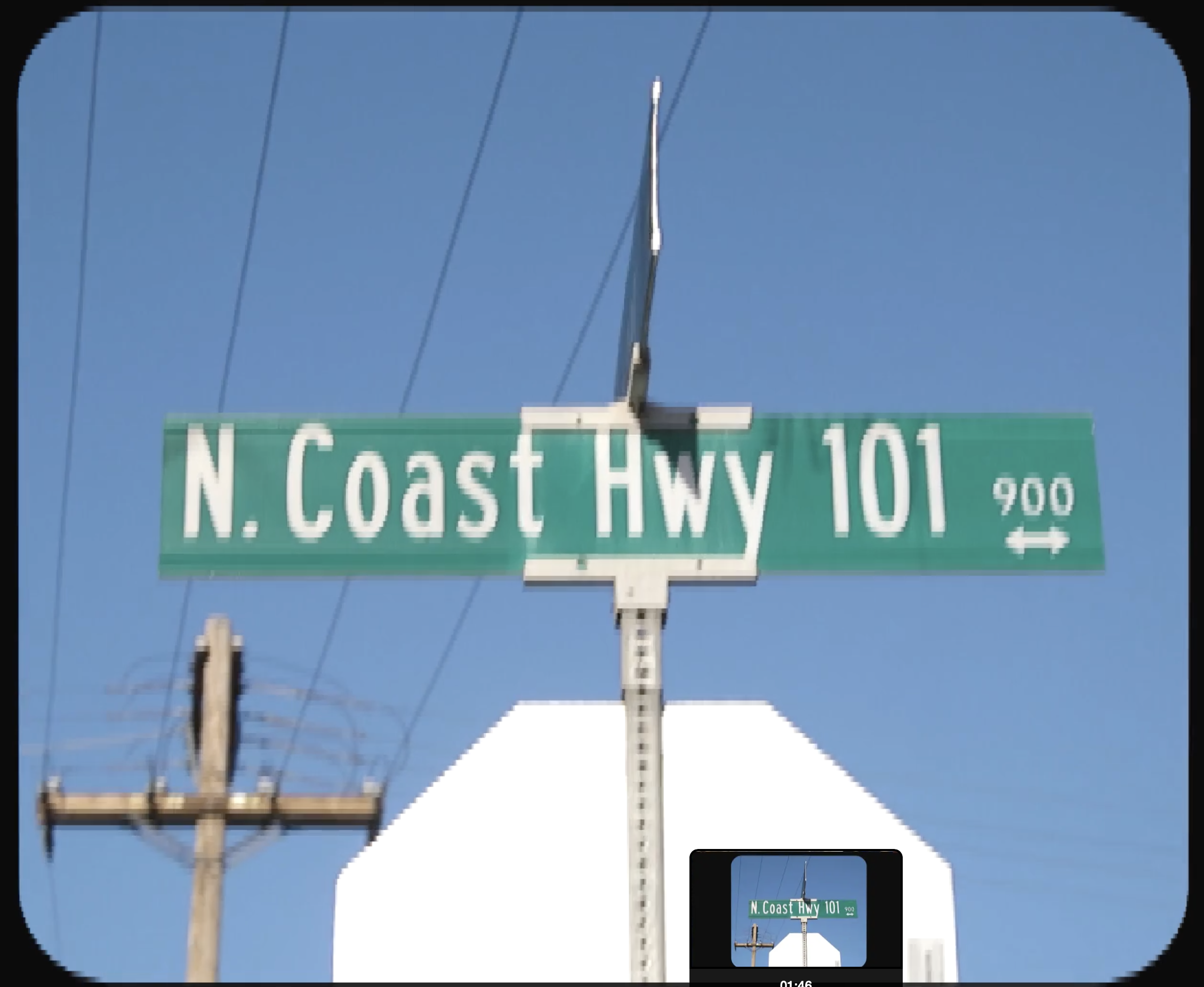 Green highway sign reading 'N. Coast Hwy 101' with a clear blue sky background, utility poles, and power lines visible.